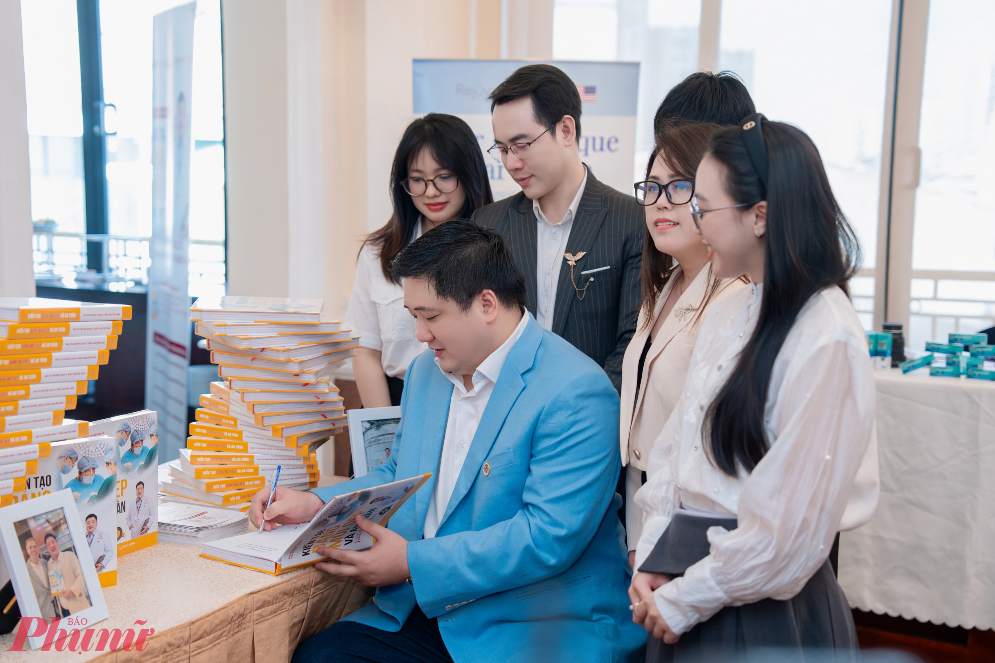 Bác sĩ Trần Nguyên Giáp ký tặng sách cho khách mời tham dự họp báo.