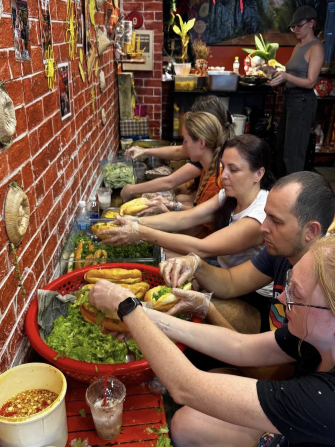 Nhóm du khách Nga cùng nhau chuẩn b5i món bánh mì để gửi đến người dân vùng lũ - Ảnh: Jain Pavlova