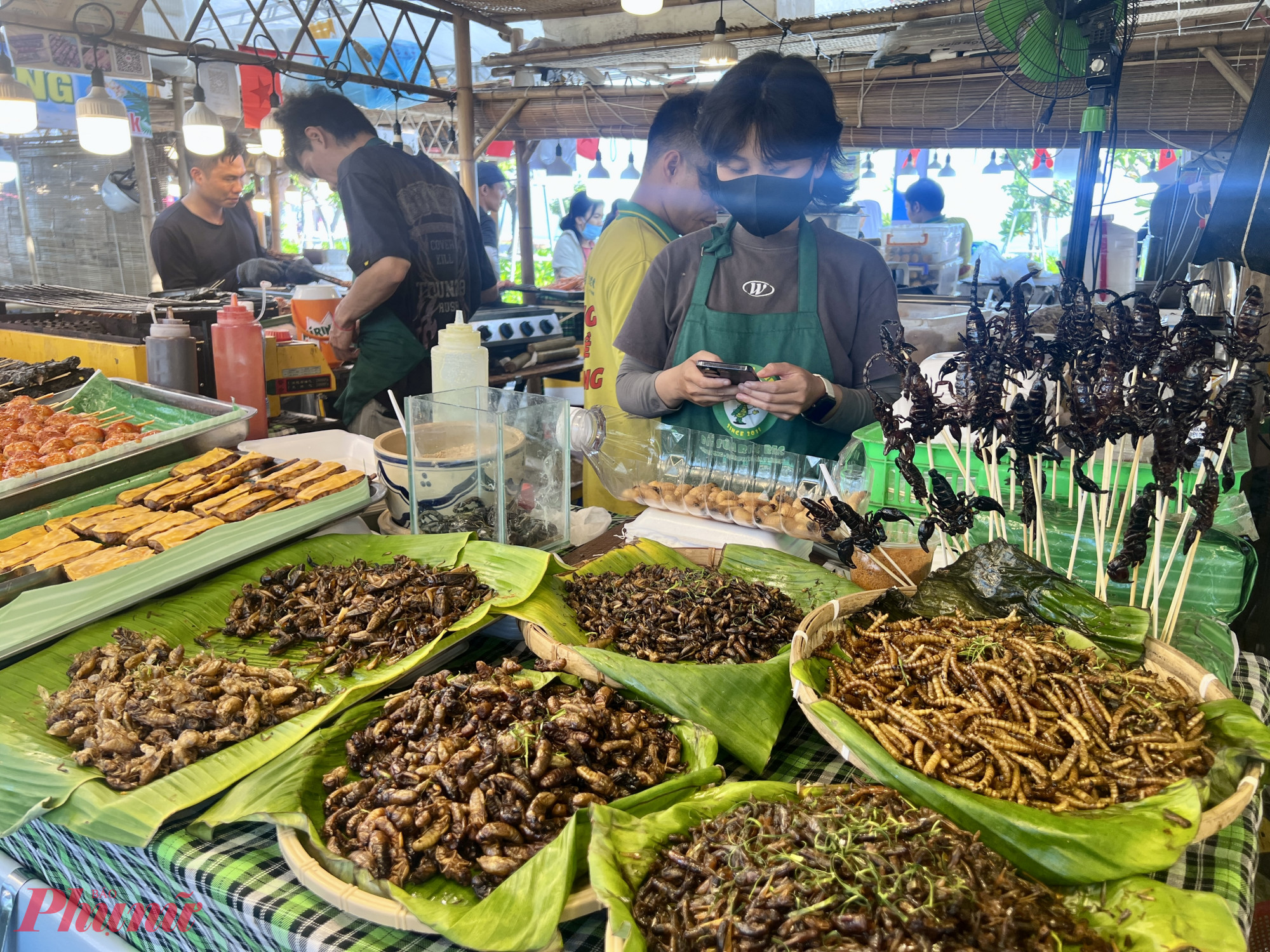 Trong khi đó, một gian hàng lại bày bán nhiều loại côn trùng như đuông dừa, bọ cạp, dế, ấu trùng nhộng,… khiến nhiều khách tò mò.