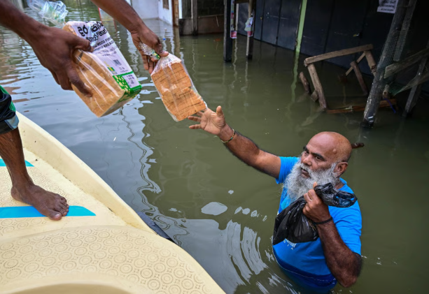 Một người đàn ông phân phát bánh mì cho các nạn nhân lũ lụt ở ngoại ô Colombo hôm thứ Bảy. Ít nhất 123 người đã thiệt mạng sau khi cơn bão đổ bộ vào đất nước họ. Ảnh: AFP