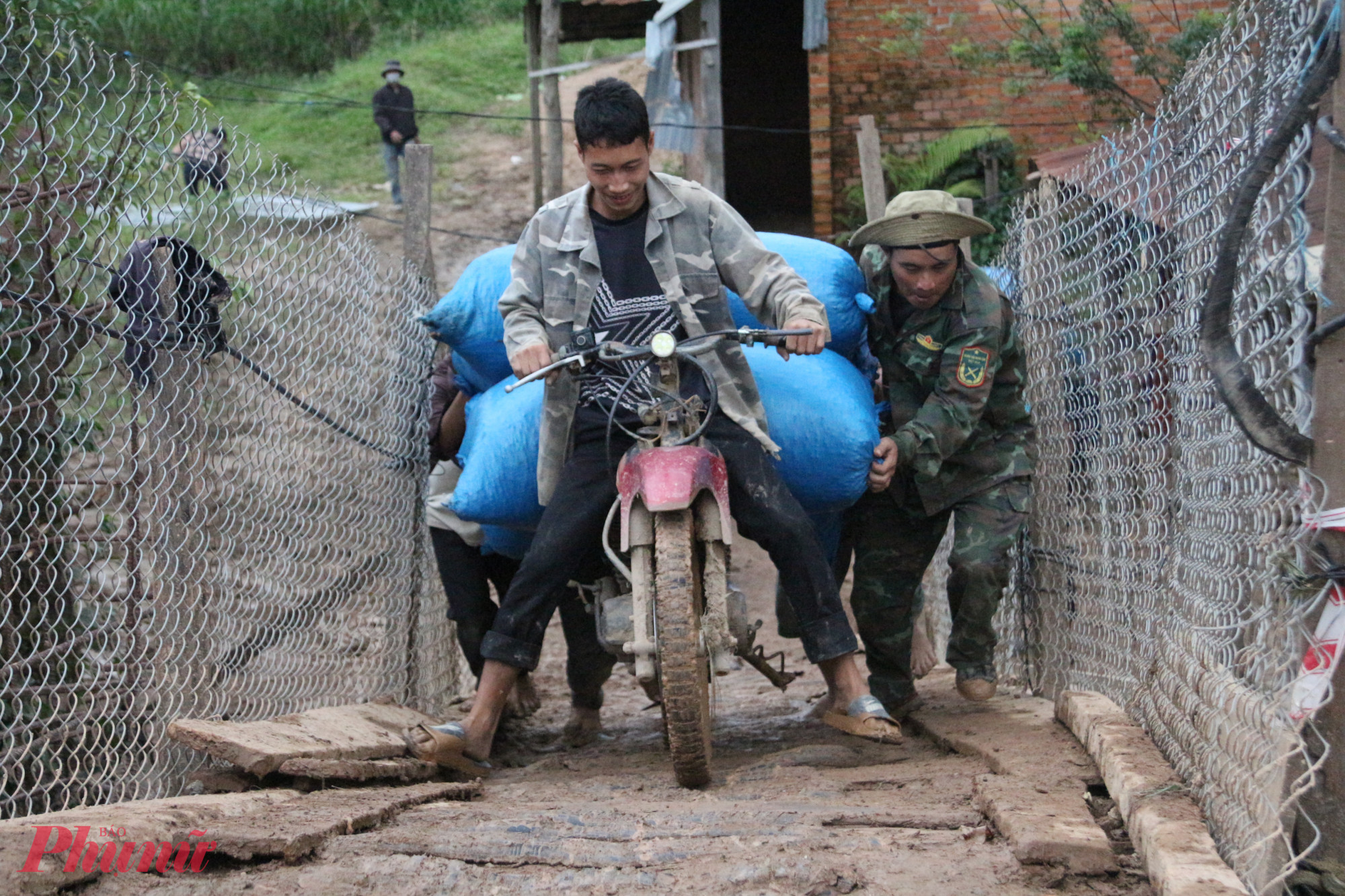 Người dân hỗ trợ nhau vận chuyển nông sản vượt qua đoạn cầu tạm trơn trượt.