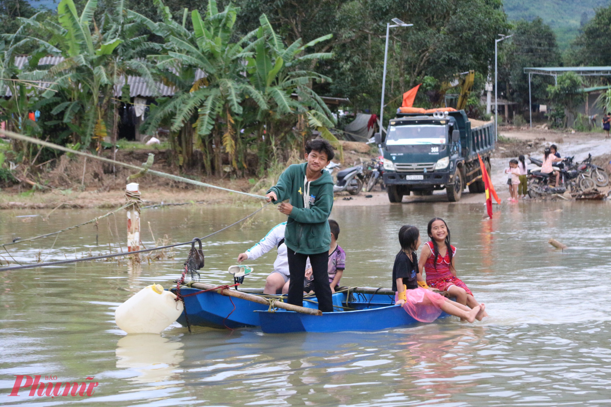 Người dân phải dùng hai chiếc ghe nhỏ do chính quyền và lực lượng chức năng hỗ trợ, rồi bám theo sợi dây cáp cố định để vượt qua đoạn đường ngập. 