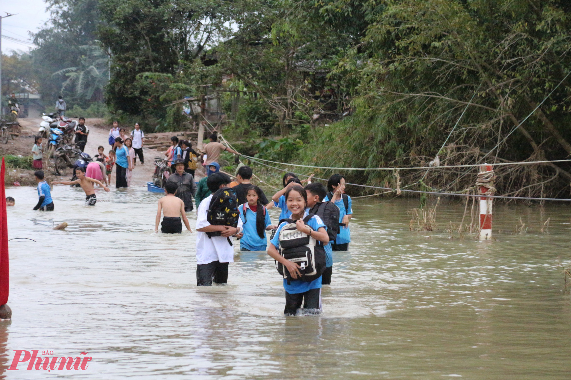 Trên đường đi học về, nhiều em học sinh lội qua đoạn nước ngập để về thôn Ea Hăn.