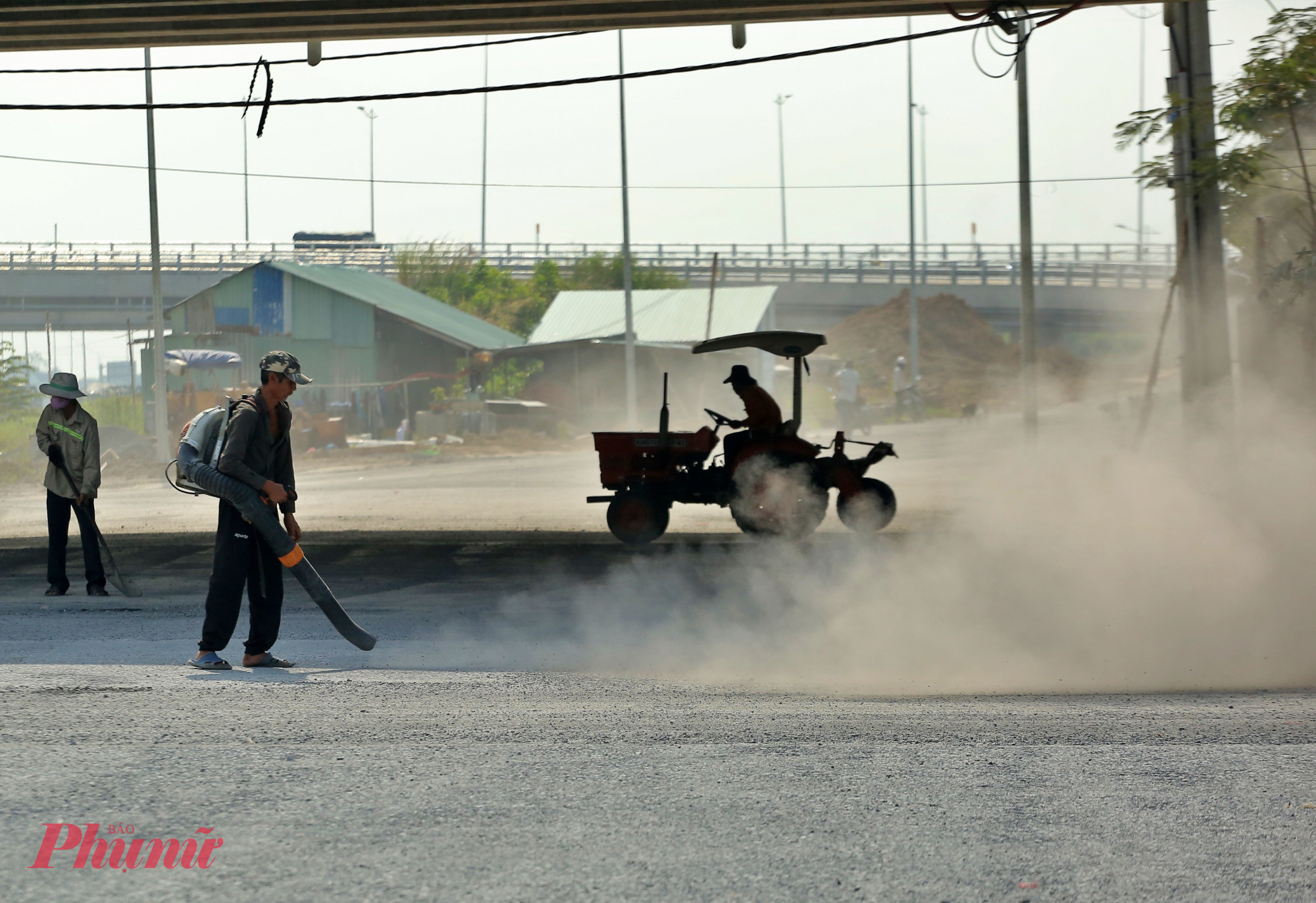 Công nhân đang thổi bụi, đất đó nhỏ rơi vãi mặt đường trước khi thi công thảm nhựa mặt đường.