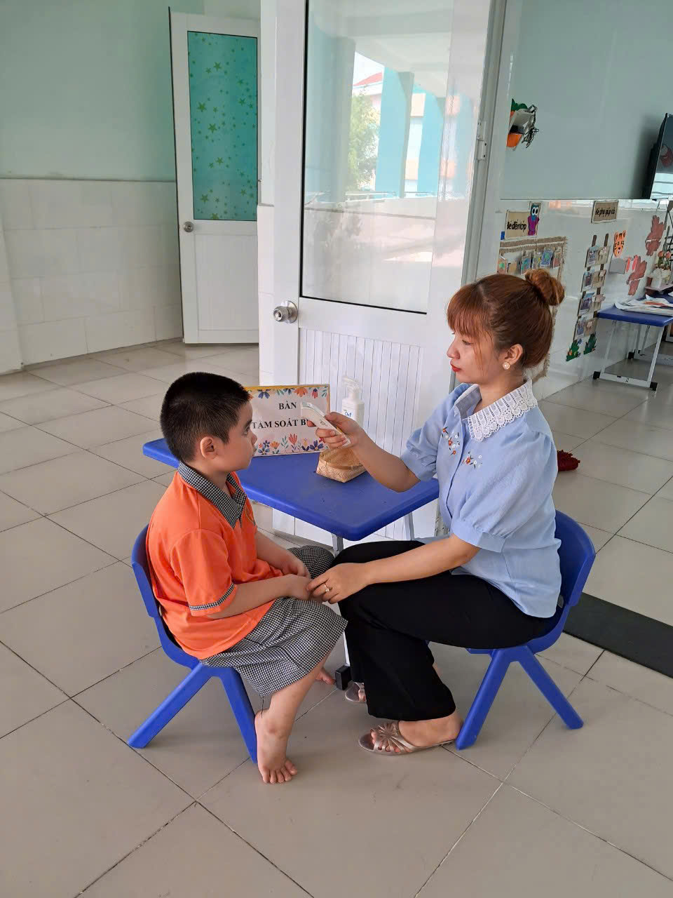 Giáo viên Trường mầm non Tân Phong kiểm tra các dấu hiệu bệnh cho trẻ trước khi vào lớp - Ảnh: T.T.