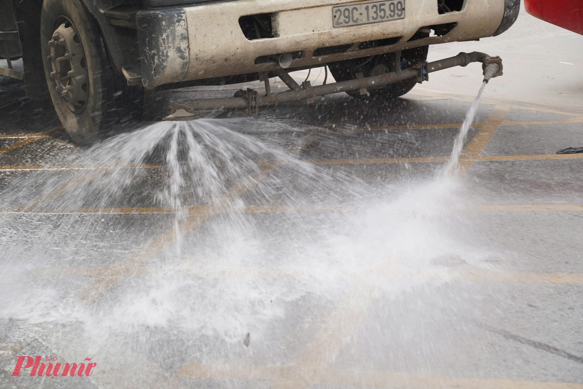 Xe rửa đường đang phun nước giảm bụi trên tuyến đường thường xuyên bị phủ dày bởi lớp bụi bẩn.