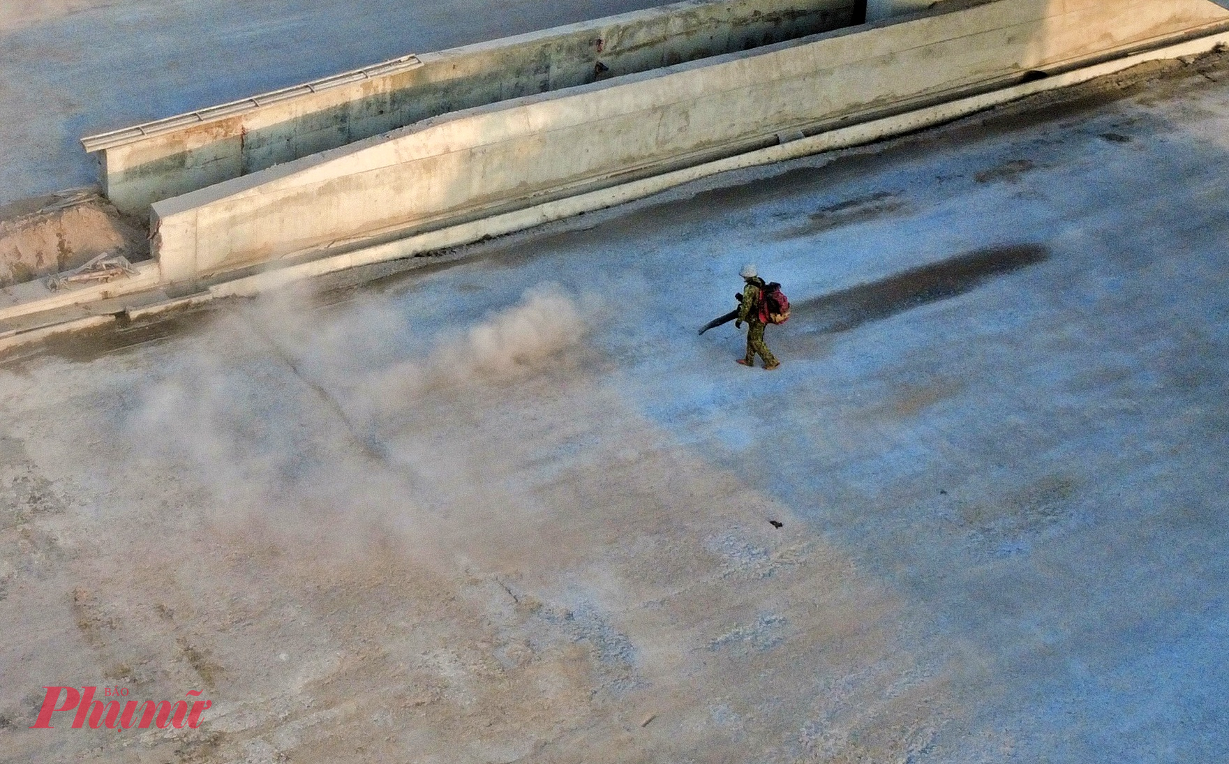 Công nhân đang thổi cát mặt đường chuẩn bị cho thảm nhựa mặt đường.