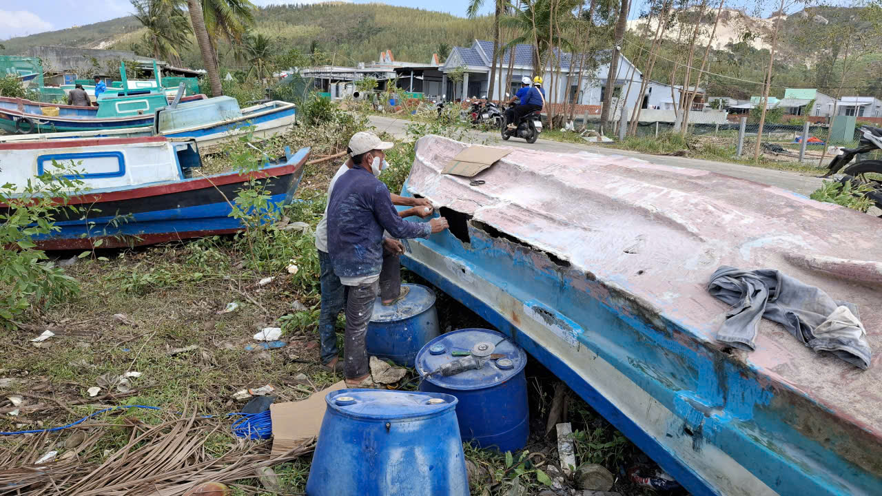 Người dân phường Sông Cầu vá ghe rách, dùng keo vá chỗ rách bằng nhựa composite- Ảnh: Mạnh Hoài Nam