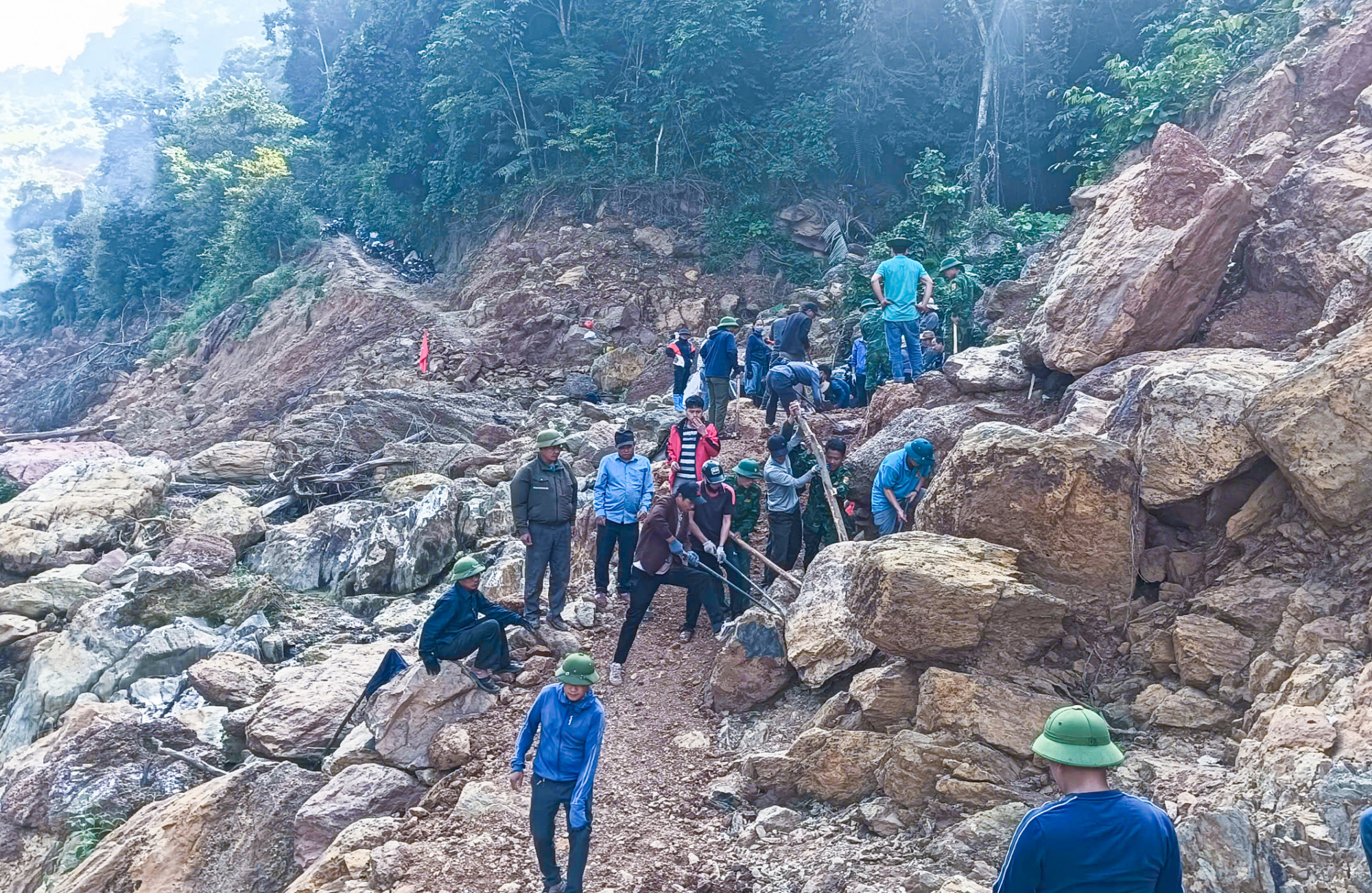 Máy móc không vào được, lực lượng chức năng và người dân phải dùng sức người di chuyển các tảng đá lớn - Ảnh: Khánh Trung