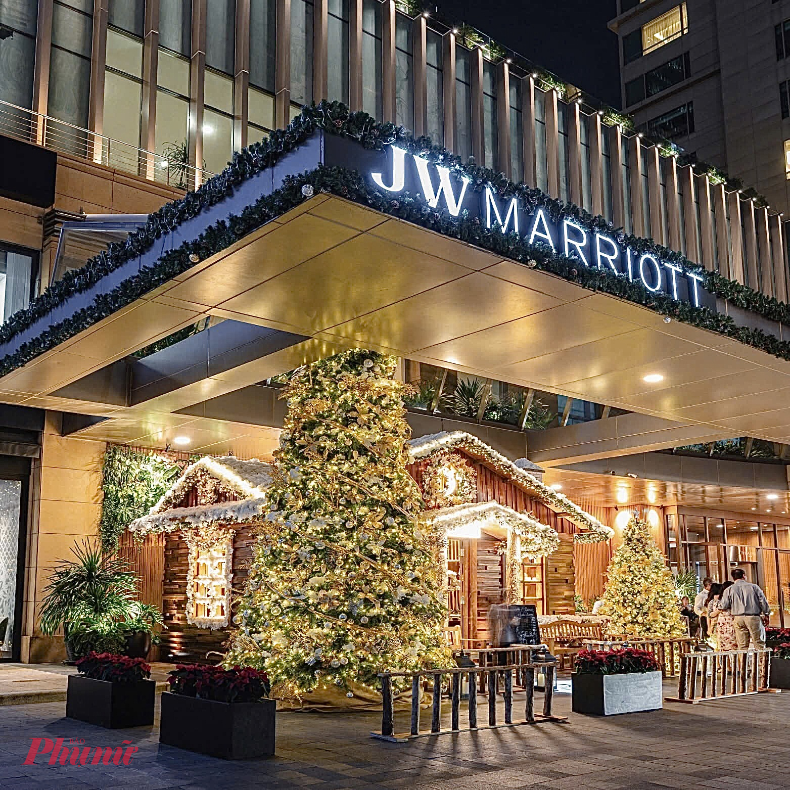 Khách sạn JW Marriott tại TPHCM khoác lên mình không khí Giáng sinh lộng lẫy với phong cách trang trí mang hơi thở châu Âu. Ngay khu vực sảnh ngoài, một ngôi nhà gỗ kiểu chalet được dựng lên như bước ra từ làng tuyết Alps, bao quanh bởi những cây thông lớn rực rỡ ánh đèn vàng. Những vòng hoa, dây thông phủ tuyết trắng khiến khung cảnh càng trở nên ấm cúng và huyền ảo.