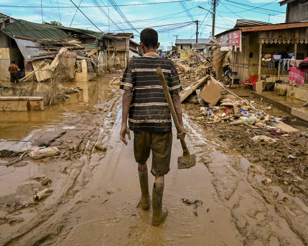 Một người đàn ông đi bộ trên một con phố phủ đầy bùn ở Aceh Tamiang ở Indonesia sau khi nước lũ rút. Ảnh: Yt Hariono / AFP / Getty Images