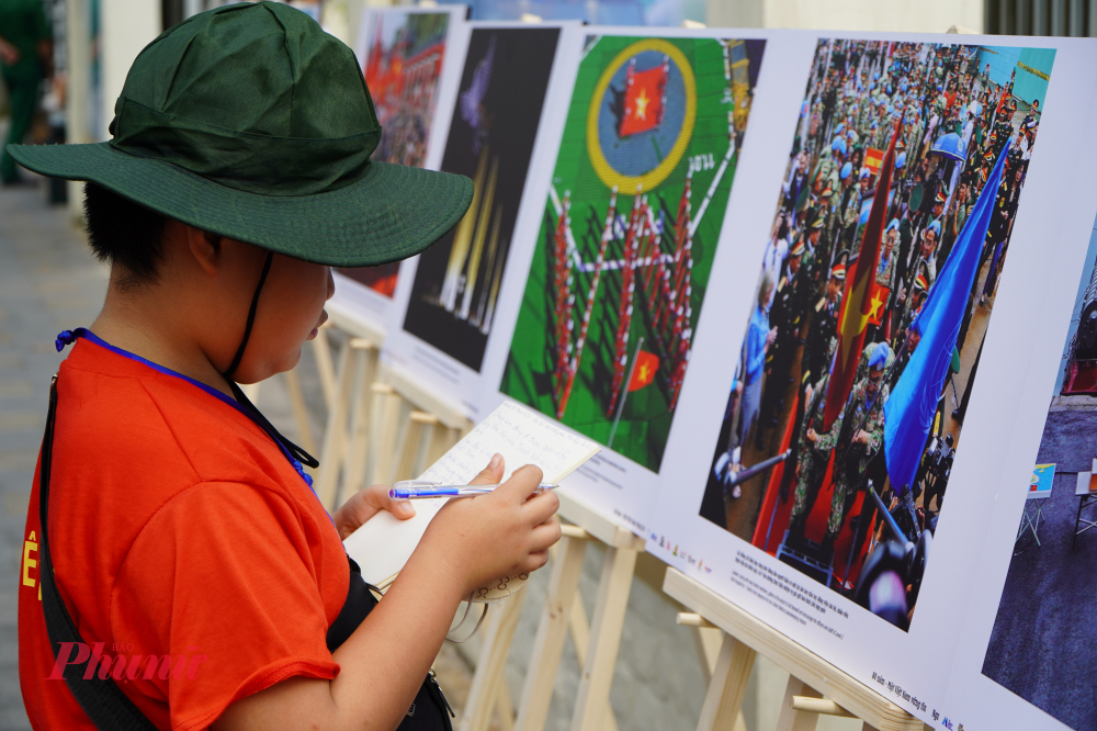 Triển lãm, ra mắt sách ảnh “80 năm – Một Việt Nam vững tin” của nhiếp ảnh gia Nguyễn Á Em Nguyễn Hải Nam chăm chú viết những dòng bày tỏ cảm xúc của bản thân khi xem tranh của nhiếp ảnh gia Nguyễn Á