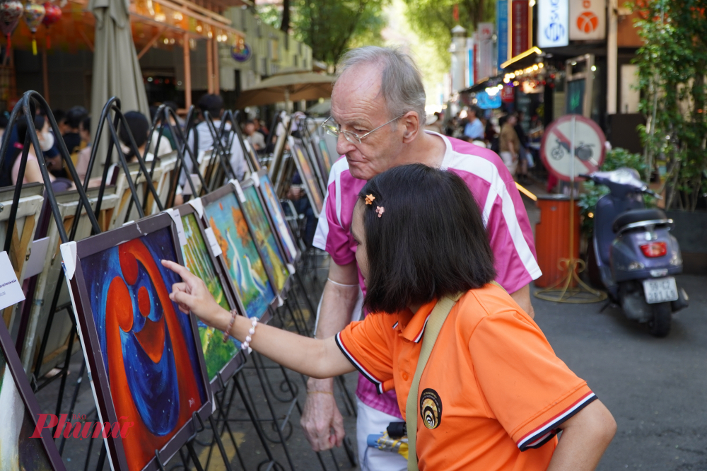 Một học viên lớp Âm Thanh Hội Họa giới thiệu tác phẩm của mình với du khách nước ngoài