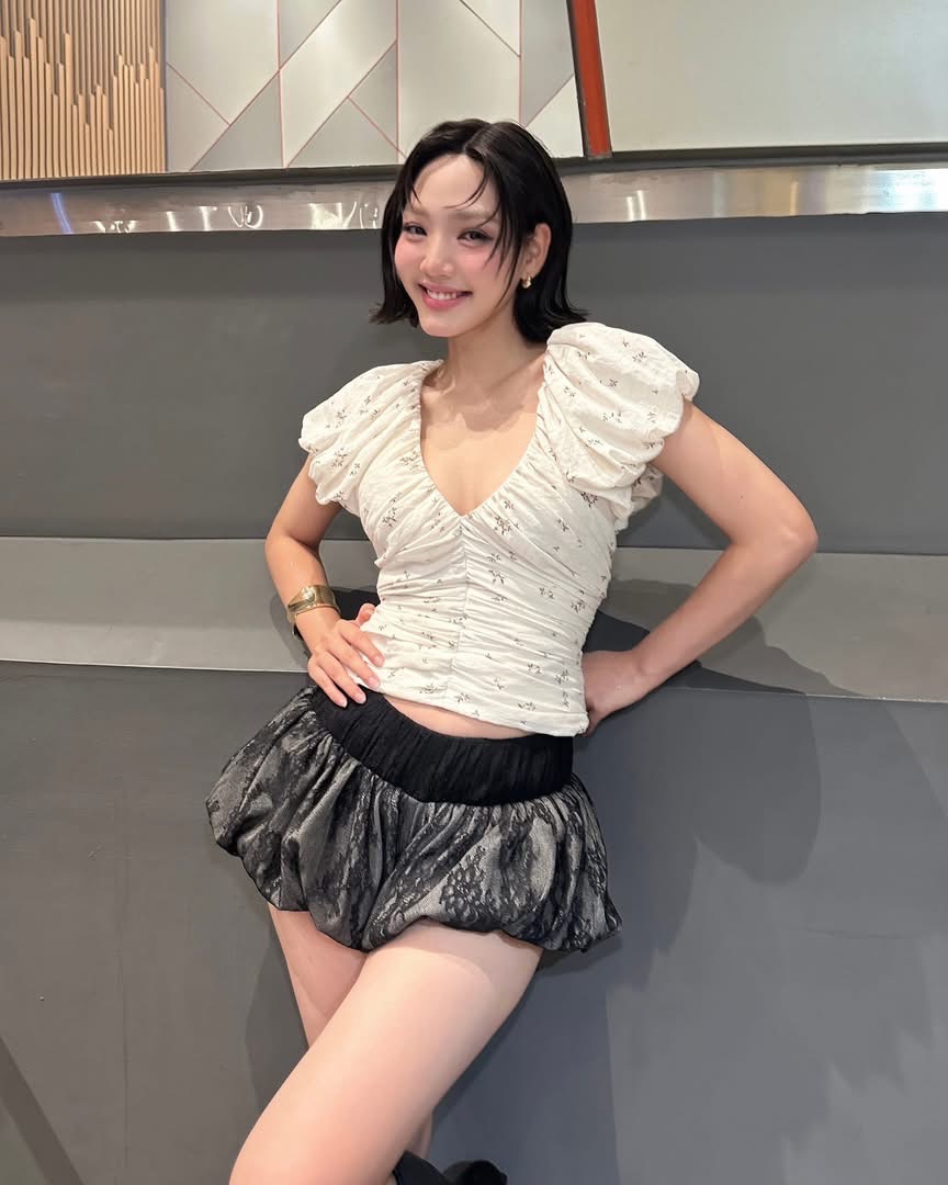 Minh Anh oát lên vẻ trẻ trung, nữ tính nhưng vẫn mang nét cá tính hiện đại. Cô lựa chọn áo trắng cổ tim với chi tiết nhún và tay phồng, vừa tôn dáng vừa gợi cảm giác mềm mại, lãng mạn. Kết hợp cùng quần short phom phồng màu đen tạo hiệu ứng tương phản, tổng thể trang phục trở nên nổi bật và thời thượng hơn.