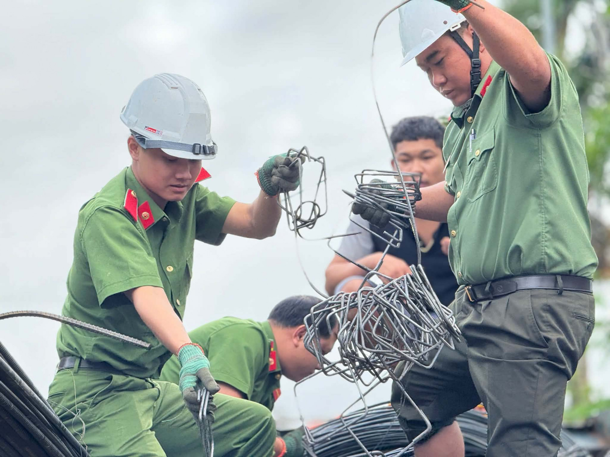 Lực lượng công an tự tay uốn từng đai cột bê tông - Ảnh: S.Đ. 