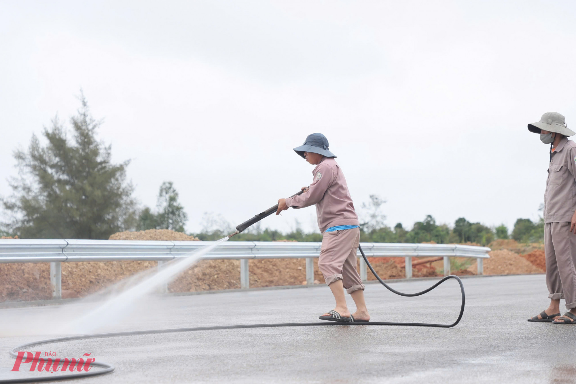 Công nhân đang tưới, rửa sạch mặt đường đã thi công hoàn thiện - Ảnh: N.H.