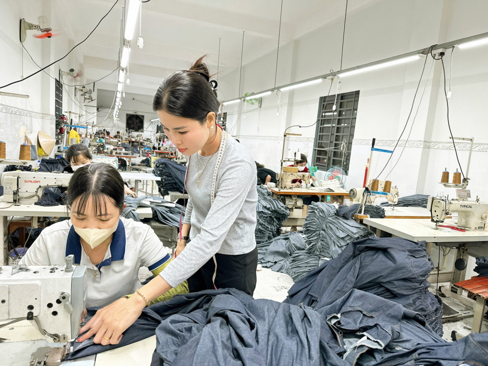 Chị Trần Thị Hòa (bìa phải) hướng dẫn công nhân làm việc trong xưởng - ẢNH: MẪN NHI