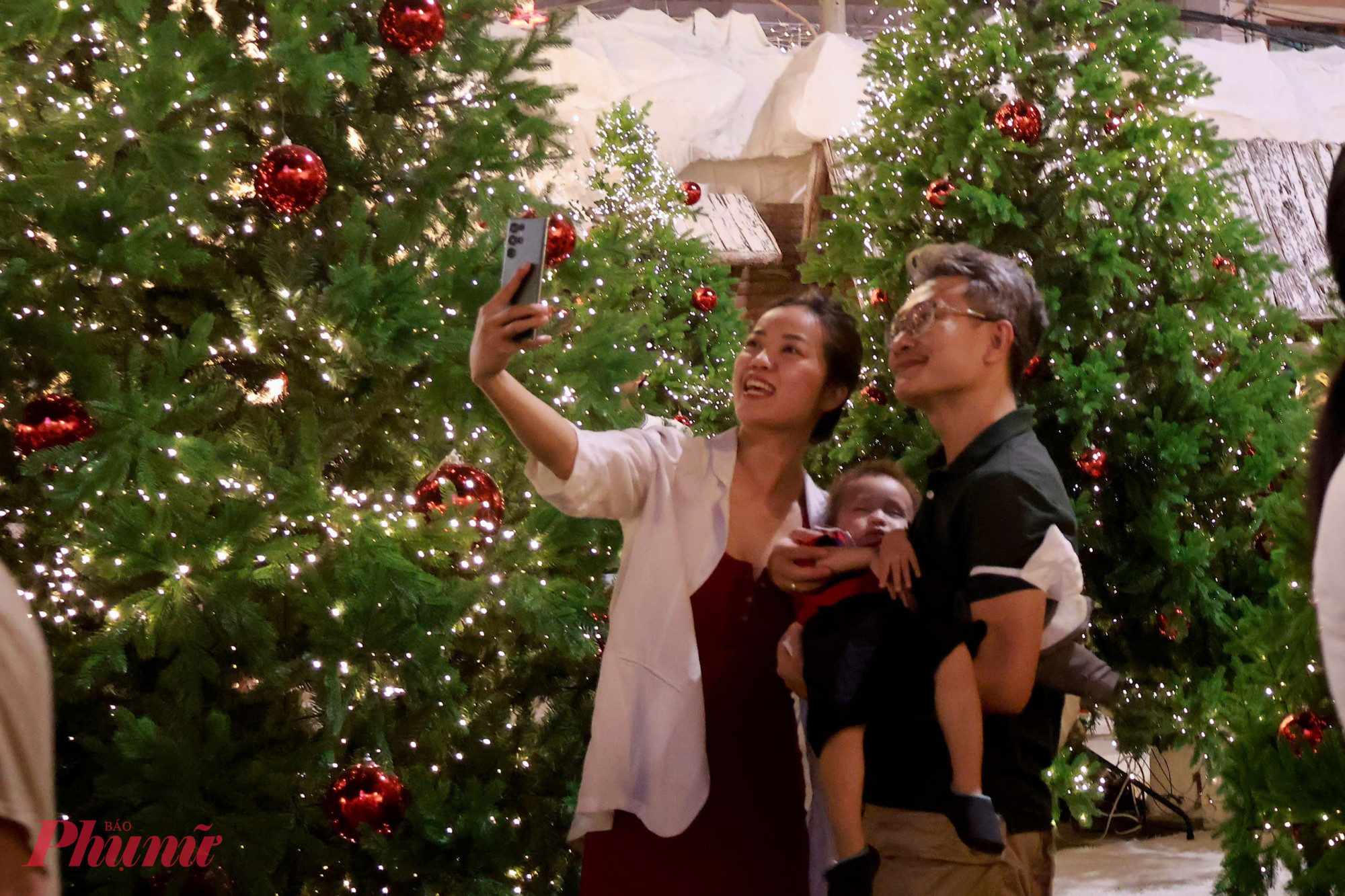 Gia đình trẻ ghi lại khoảnh khắc sum vầy bên cây thông Giáng sinh.