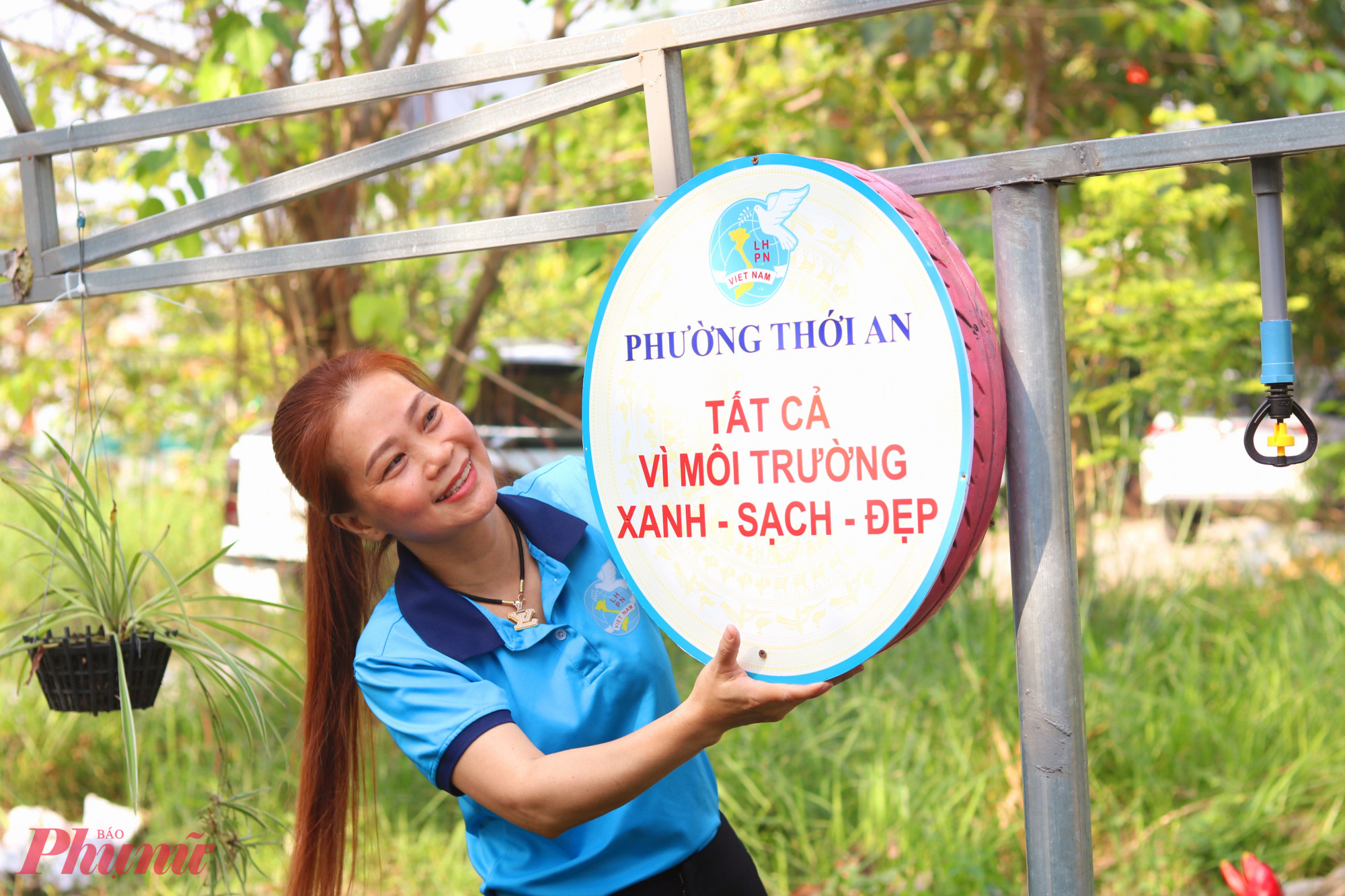 Chị Đoàn Thị Anh Đào – Chi hội trưởng Chi hội Phụ nữ khu phố 50, phường Thới An – lắp các bánh xe tuyên truyền lên khung sắt. Chị cho biết, mỗi ngày, chi hội cử 2 chị phụ trách quét dọn rác và chăm sóc cây hoa trên tuyến đường - Ảnh: Mẫn Nhi