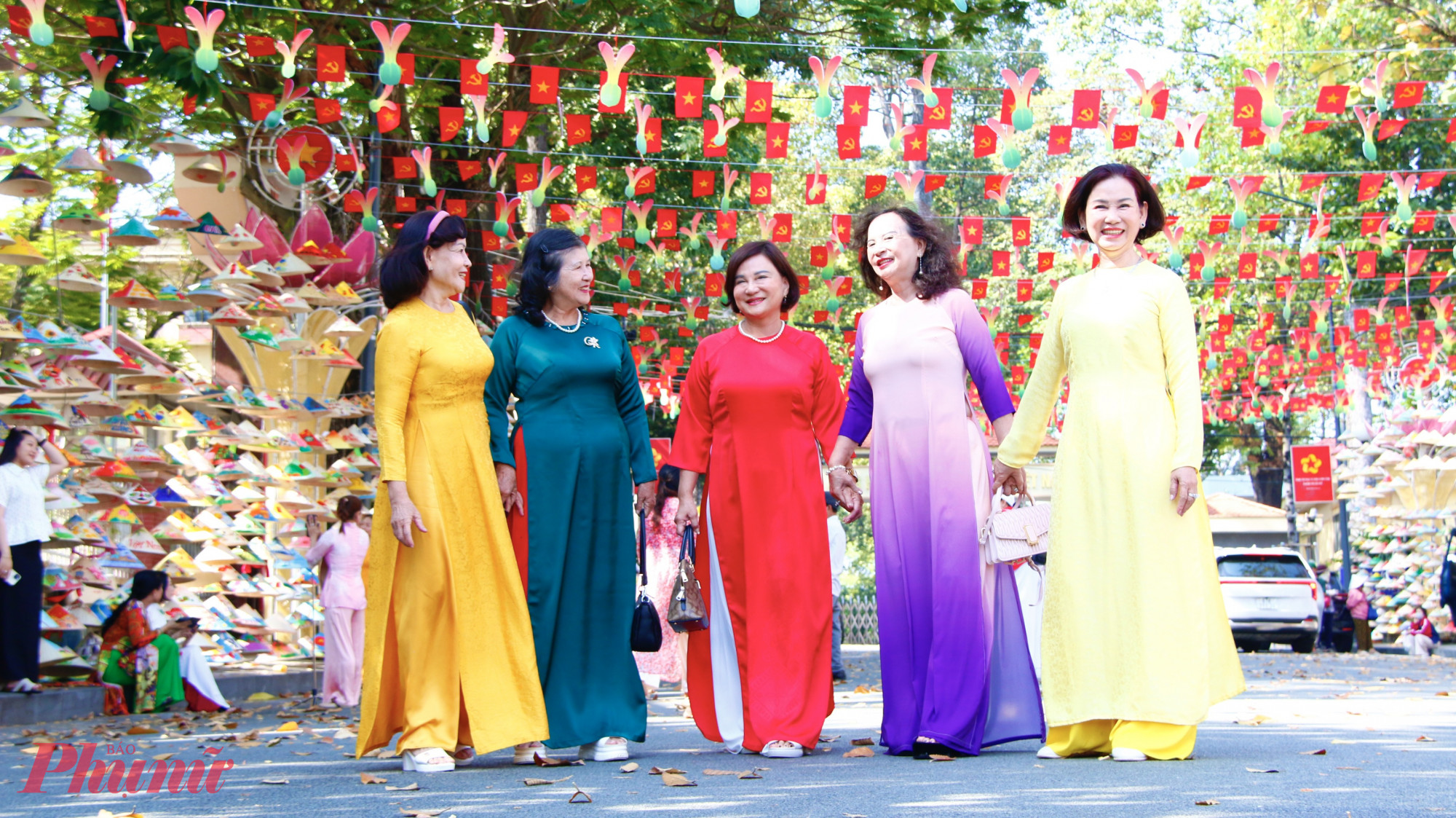 Nữ cán bộ hưu trí cùng diện áo dài truyền thống chụp ảnh tại tuyến đường nón lá.