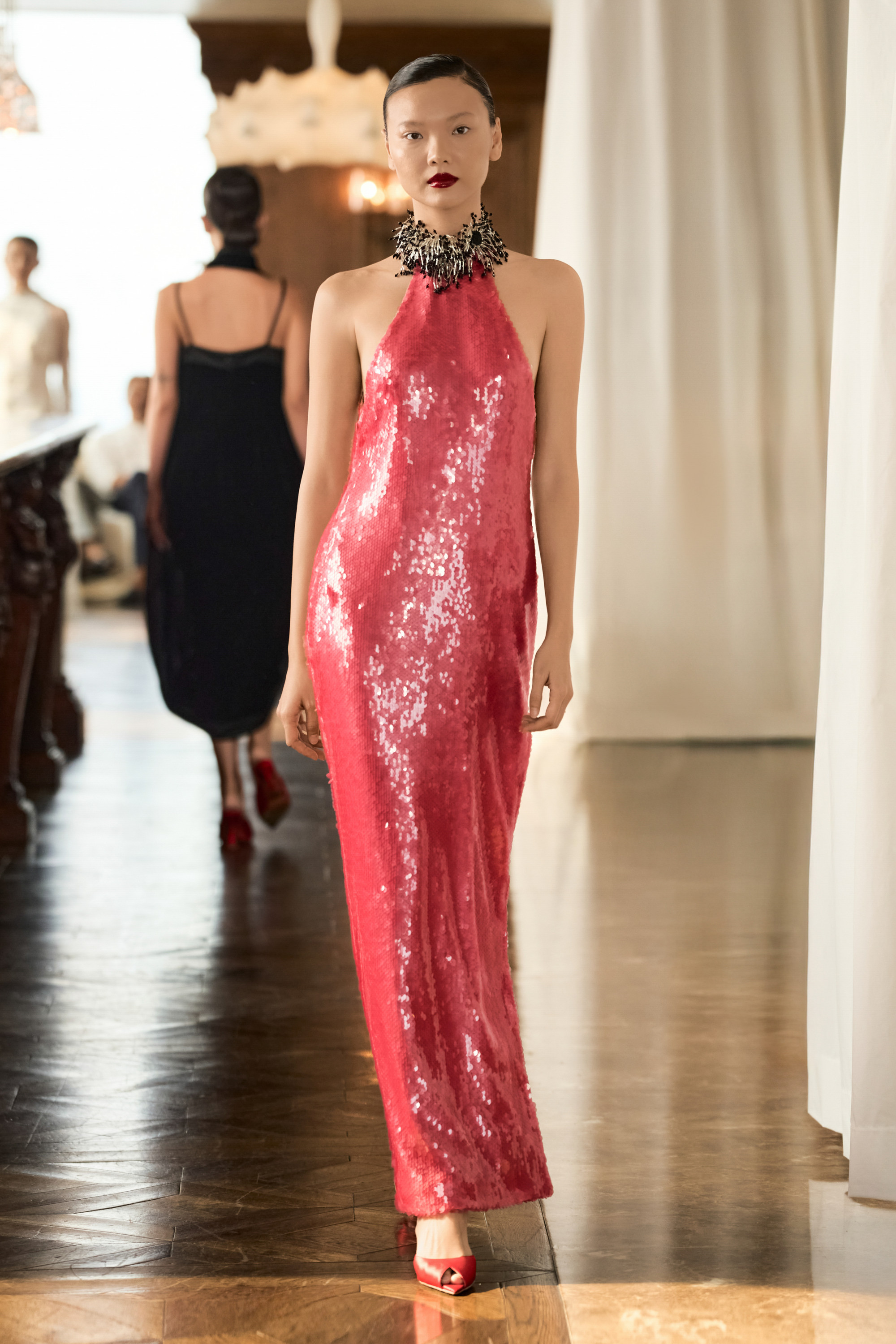 Các thiết kế có phom dáng mềm mại nhưng có kỷ luật, ôm theo đường cong tự nhiên của cơ thể, thay vì áp đặt hình thể. Chất liệu được xử lý để sống cùng người mặc: rủ nhẹ, bắt sáng tinh tế và chuyển động theo từng nhịp bước, tạo nên cảm giác liền mạch giữa cơ thể và trang phục.