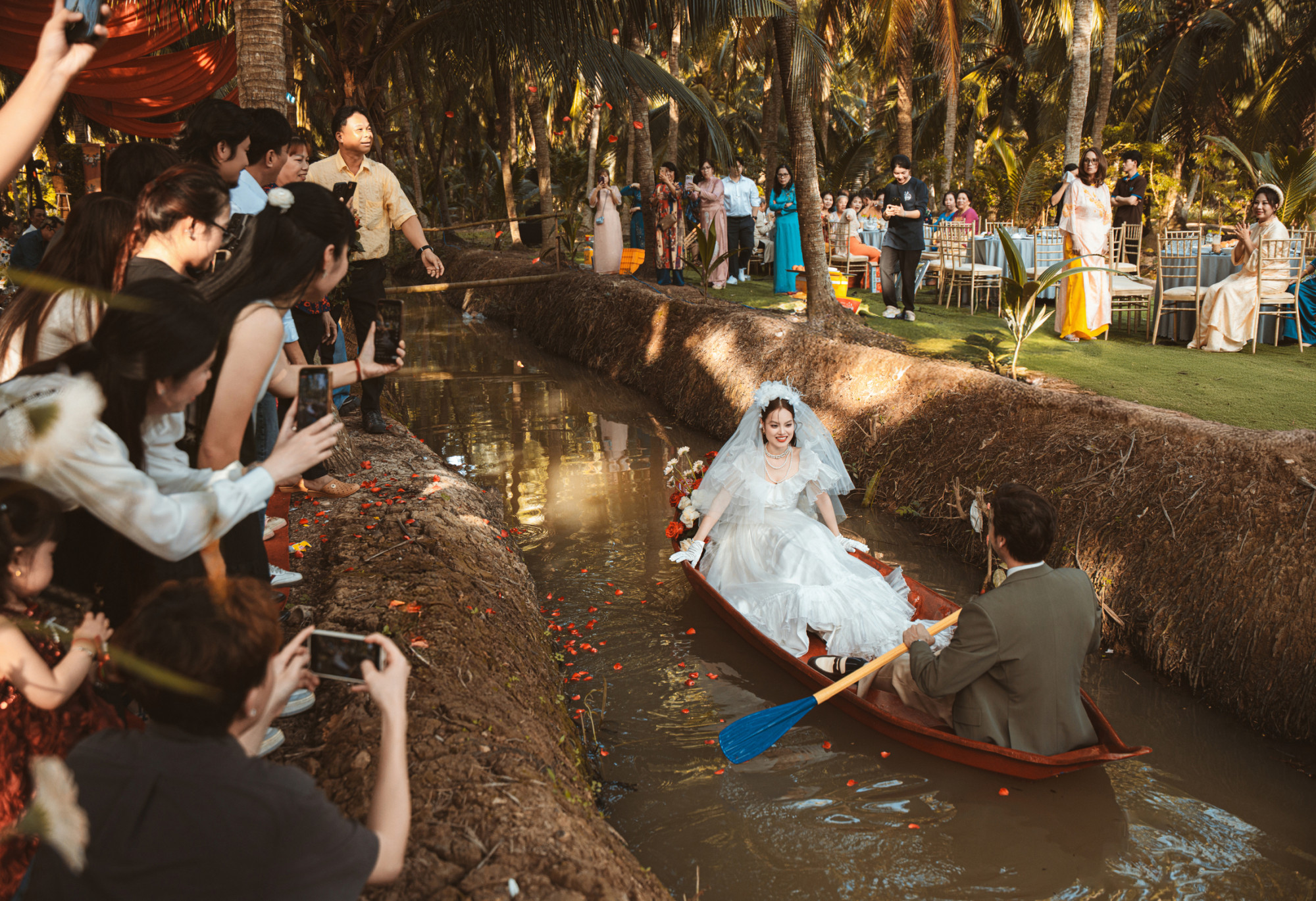 Nhiều bạn bè, người thân thích thú ghi lại cảnh cô dâu và chú rể chèo xuồng giữa vườn dừa.