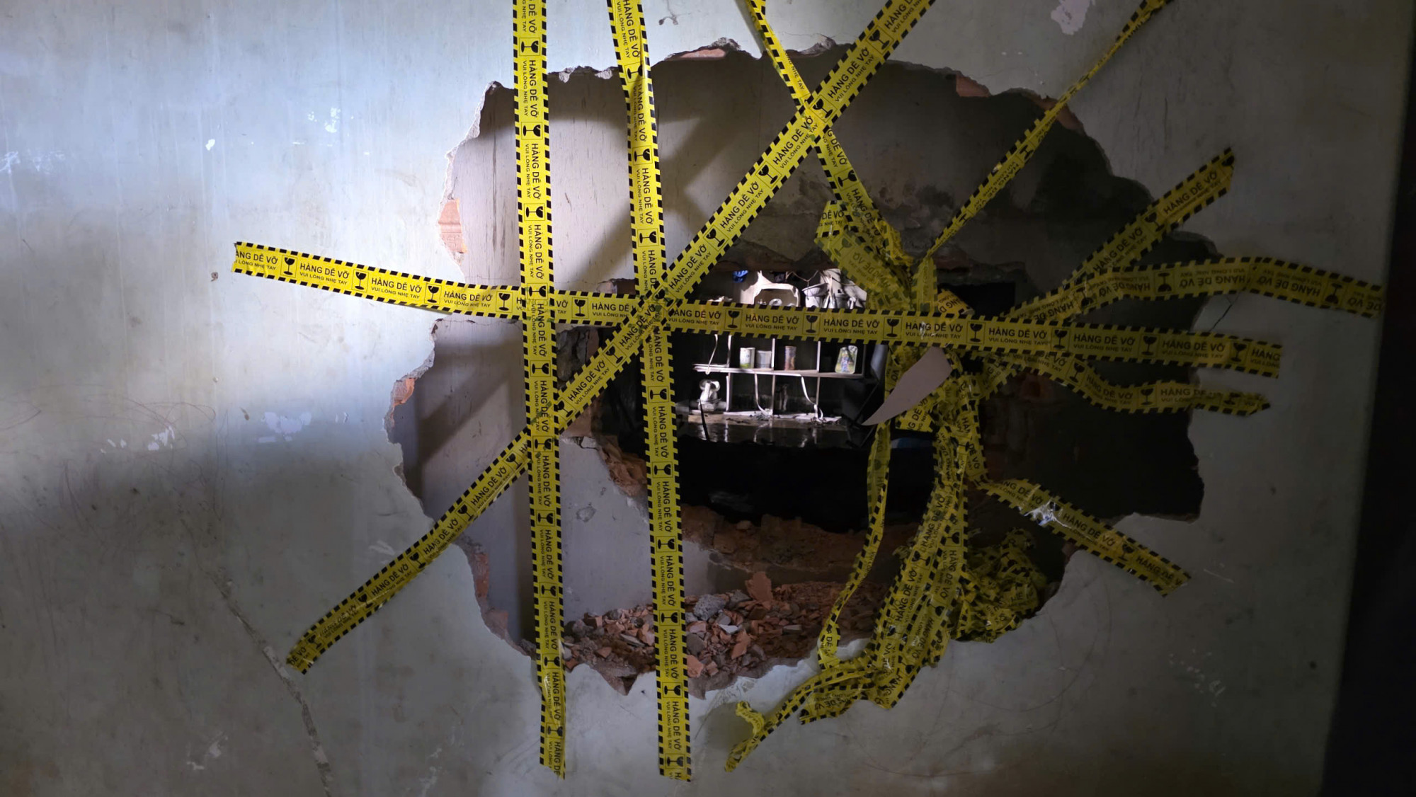 Lực lượng chức năng và người dân đập tường để tiếp cận hiện trường - Ảnh: N.H.