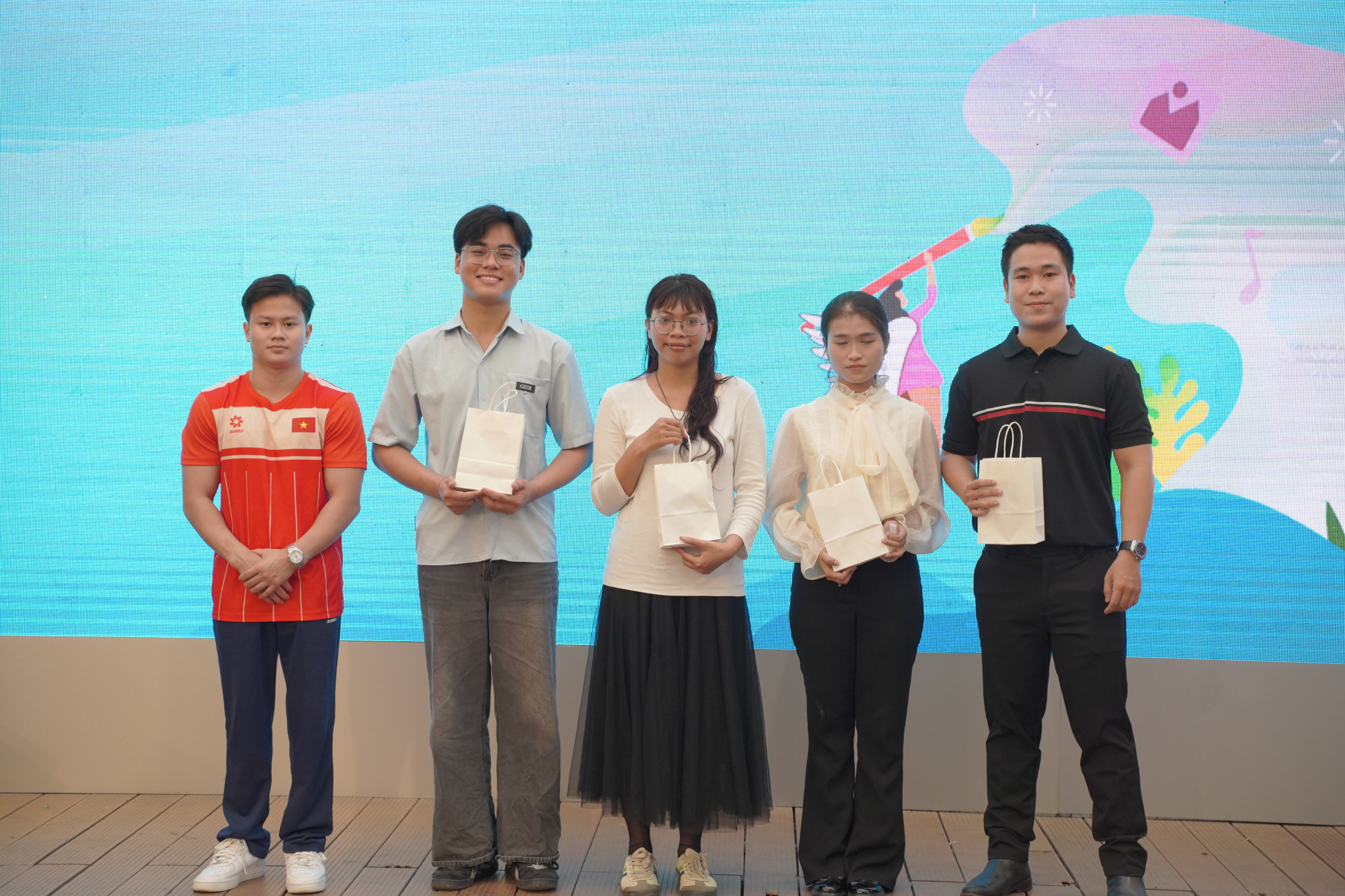 VĐV Nguyễn Văn Khánh Phong (bìa trái) - Huy chương vàng SEA Games 33 môn Vòng treo nam trao quà cho các khán giả tham gia minigames - Ảnh: BTC