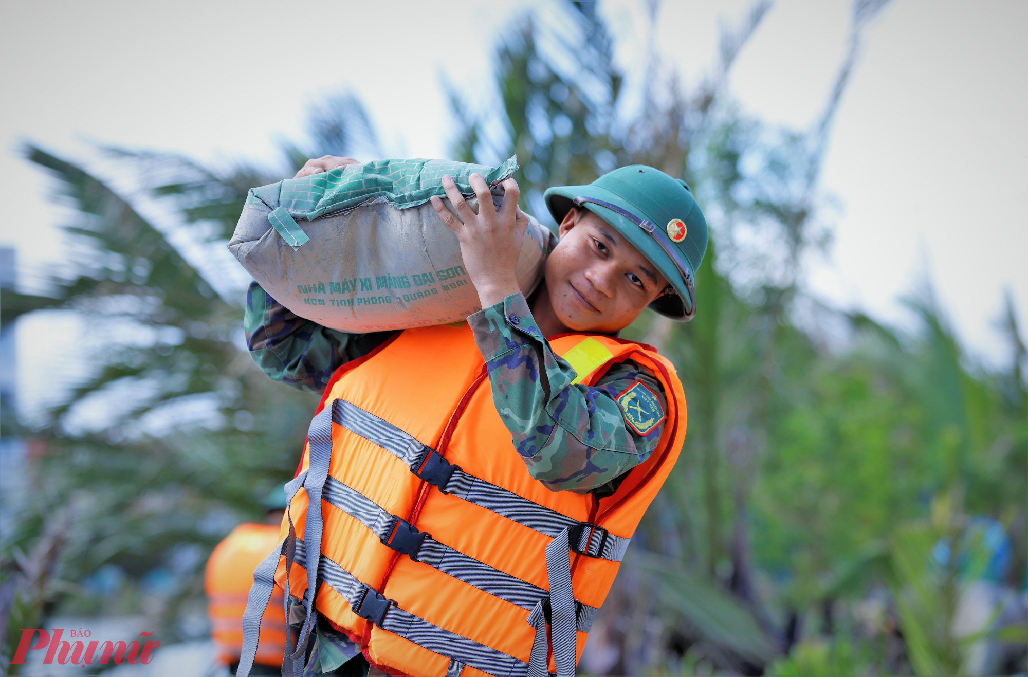 Từng bao xi măng được các chiến sĩ vác từ dưới ghe, thuyền lên bờ - Ảnh: Tuệ Lâm.