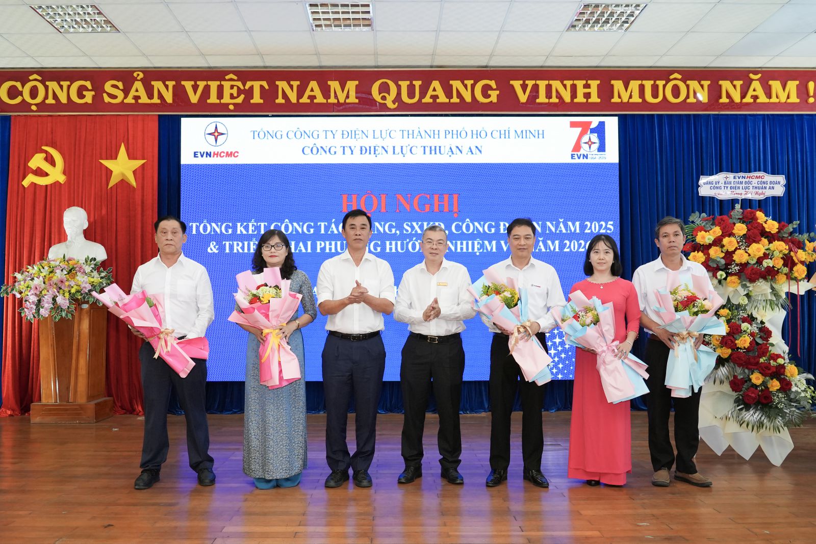 Ông Nguyễn Văn Thanh - Phó bí thư Đảng ủy, Tổng giám đốc (giữa) - và ông Nguyễn Minh Tùng - thành viên HĐTV EVNHCMC (thứ ba từ trái sang) - trao hoa chúc mừng tập thể, cá nhân Công ty Điện lực Thuận An vì đã được đề xuất khen tặng giấy khen của Tập đoàn Điện lực Việt Nam - Ảnh: EVNHCMC