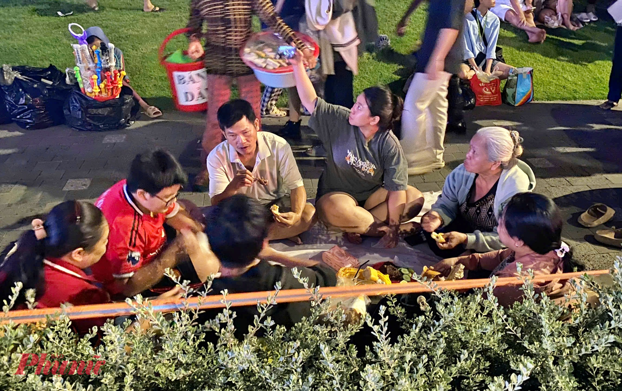 Nhiều gia đình đến từ sớm để chọn chỗ, ngồi quây quần ăn uống để chờ thưởng thức pháo hoa chào đón năm mới 2026.