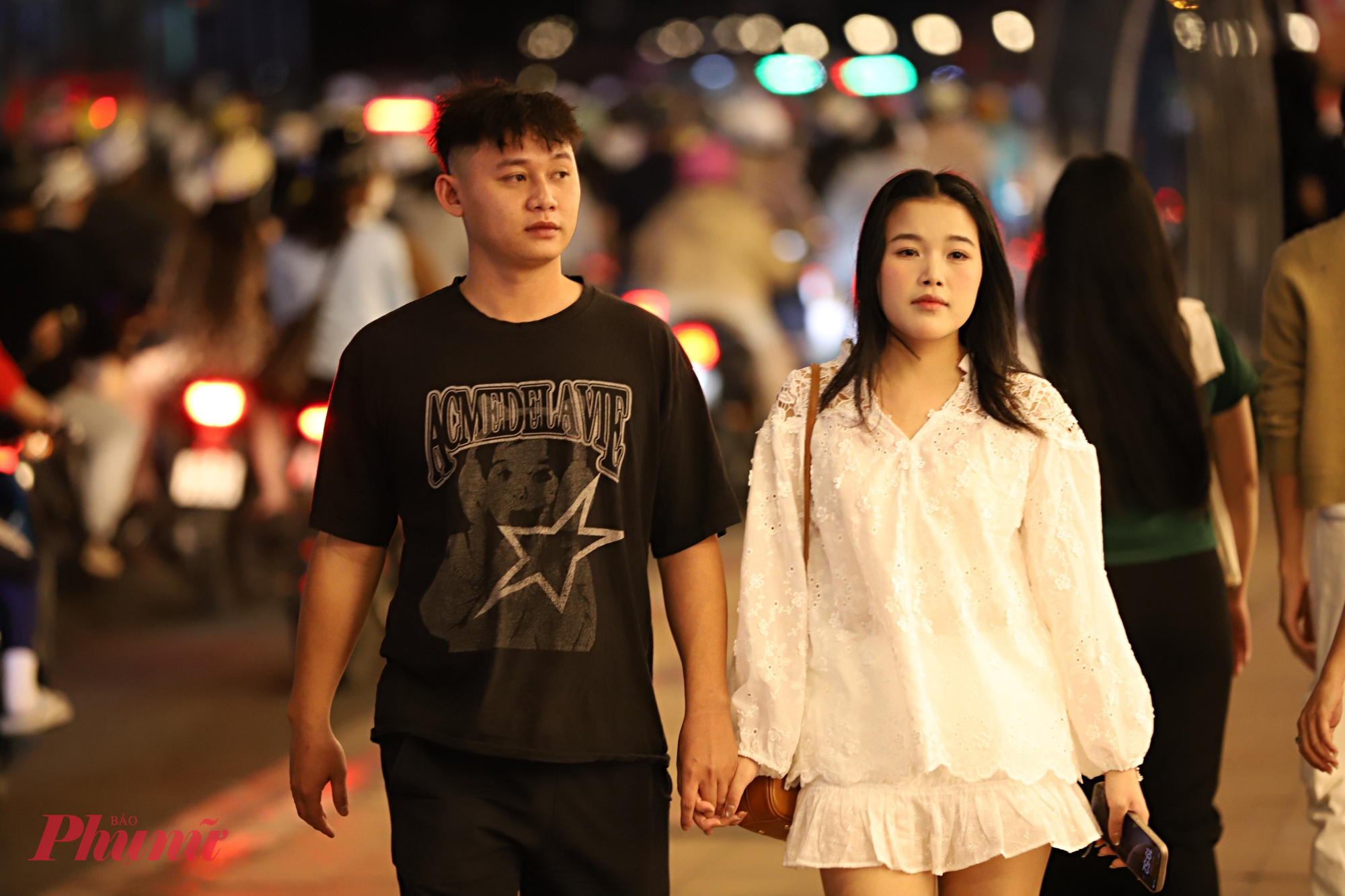 Đôi bạn trẻ dạo phố trong buổi tối cuối năm để chờ thời khắc năm mới 2026.