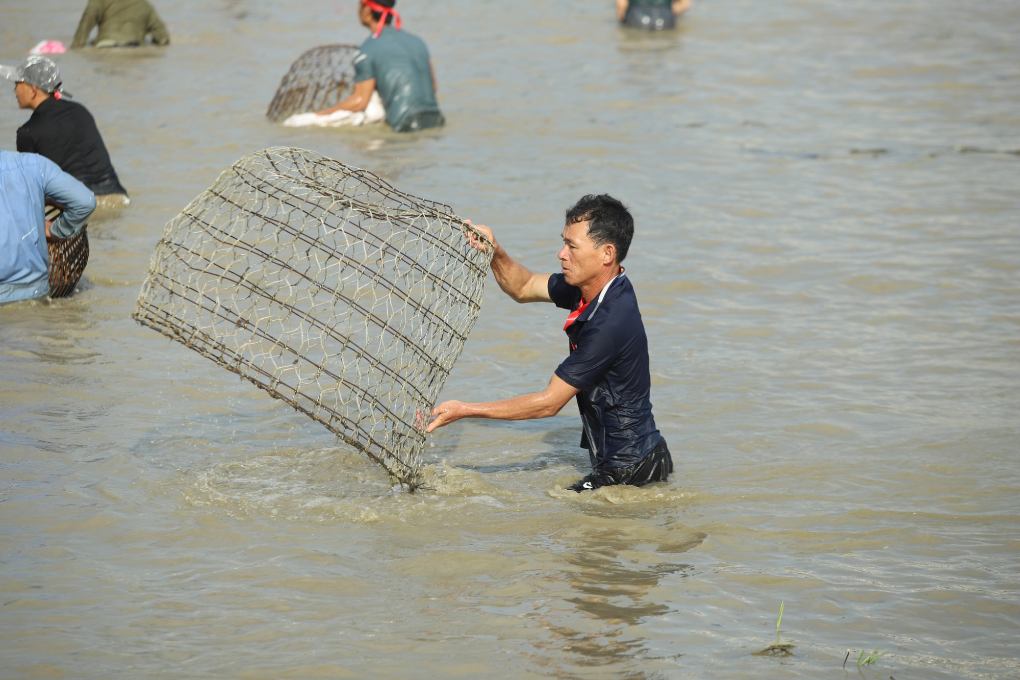 Một số người còn mang cả lồng sắt nhốt gia cầm ra bắt cá - Ảnh: Rạng Đông