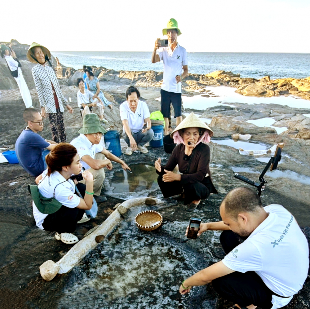 Bà Nguyễn Thị Vân (đội nón) thuyết minh với du khách về cách làm muối trên gành đá  đã được duy trì từ xưa đến nay - ẢNH: G.C.
