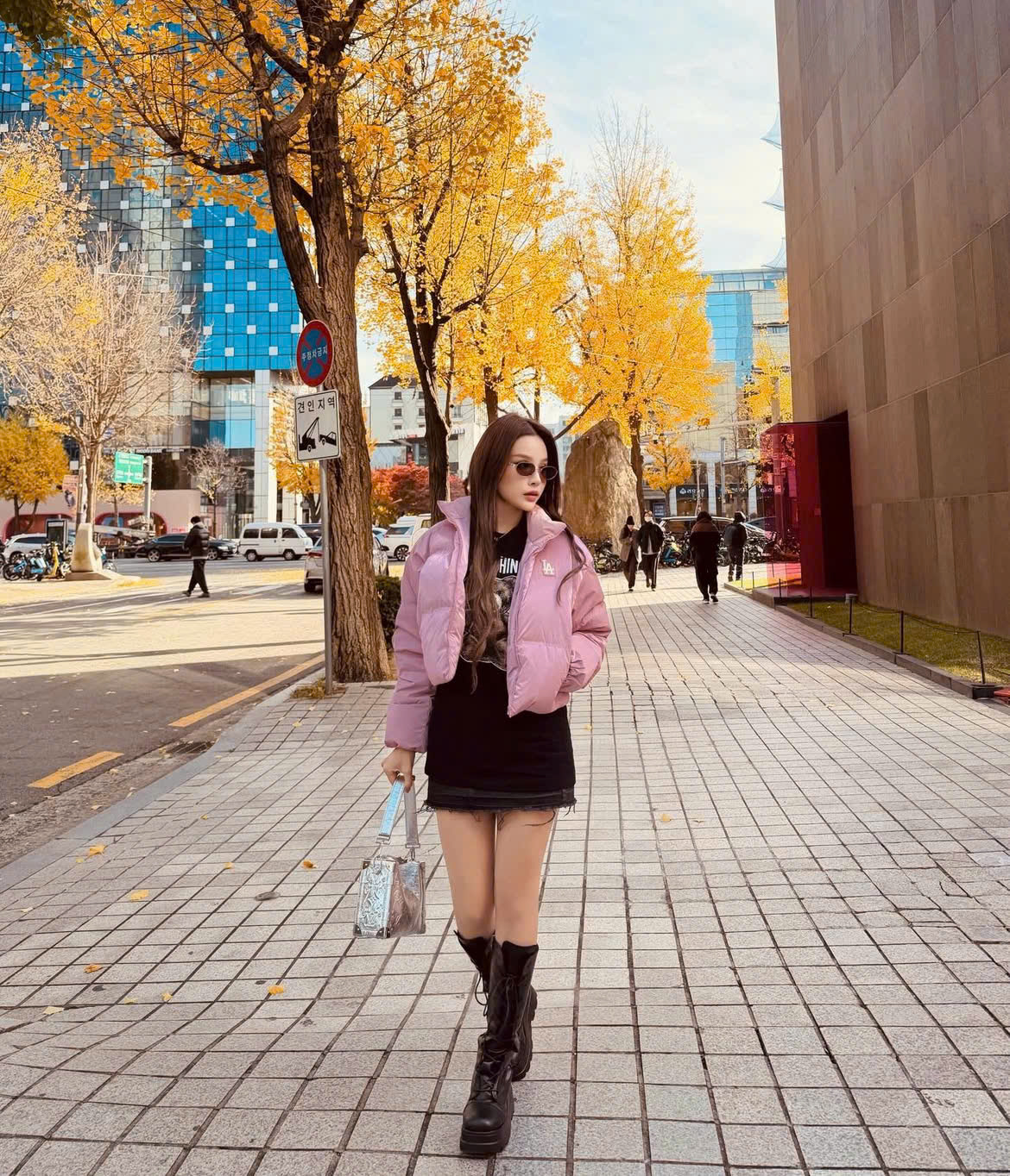 Đón năm mới ở Seoul (Hàn Quốc), Huyền Baby mang đến hình ảnh trẻ trung, năng động pha chút ngọt ngào đúng tinh thần street style của xứ kim chi. Cô phối áo phao dáng ngắn màu hồng pastel cùng váy ngắn đen và áo thun tối giản, tạo sự cân bằng giữa nữ tính và cá tính. Boots cao cổ đế dày giúp tổng thể thêm phần khỏe khoắn, tôn dáng và phù hợp tiết trời mùa đông. Phụ kiện túi xách ánh kim và kính râm mang hơi hướng thời trang đô thị, khiến set đồ vừa cool vừa dễ ứng dụng, đúng chất Seoul năng động và thời thượng.