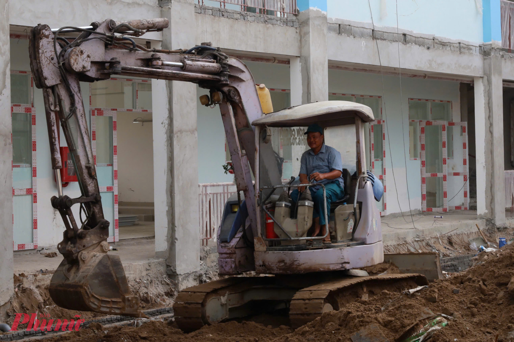 Máy xúc san lấp mặt bằng trong sân trường, đẩy nhanh tiến độ của công trình. 