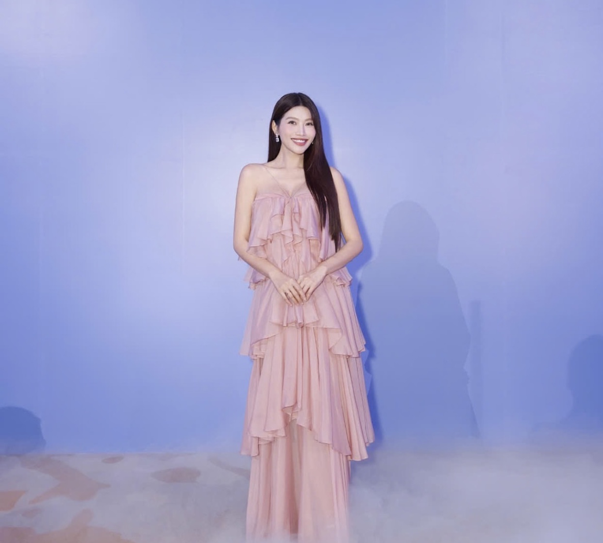 Á hậu Quỳnh Châu lựa chọn váy 2 dây xếp tầng màu hồng phấn. Thiết kế nhiều lớp chiffon mềm mại tạo hiệu ứng thon gọn, mang đến cảm giác mong manh nhưng không kém phần quyến rũ. Kiểu tóc buông thẳng tự nhiên cùng lối trang điểm trong veo giúp nhan sắc của cô thêm rạng rỡ, đúng tinh thần gợi cảm đầy tinh tế.