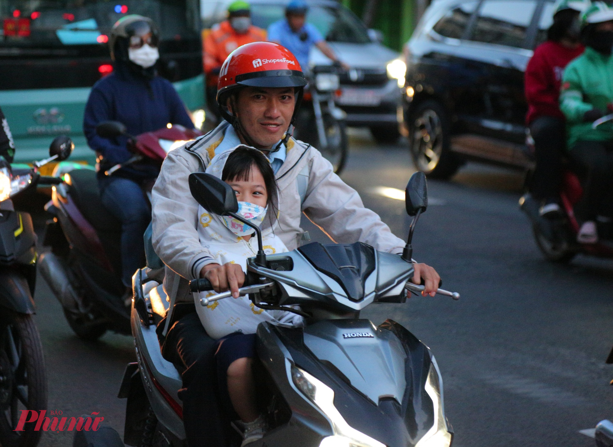 Trẻ em thích thú co ro trong chiếc áo ấm khi được cha đưa đến trường.