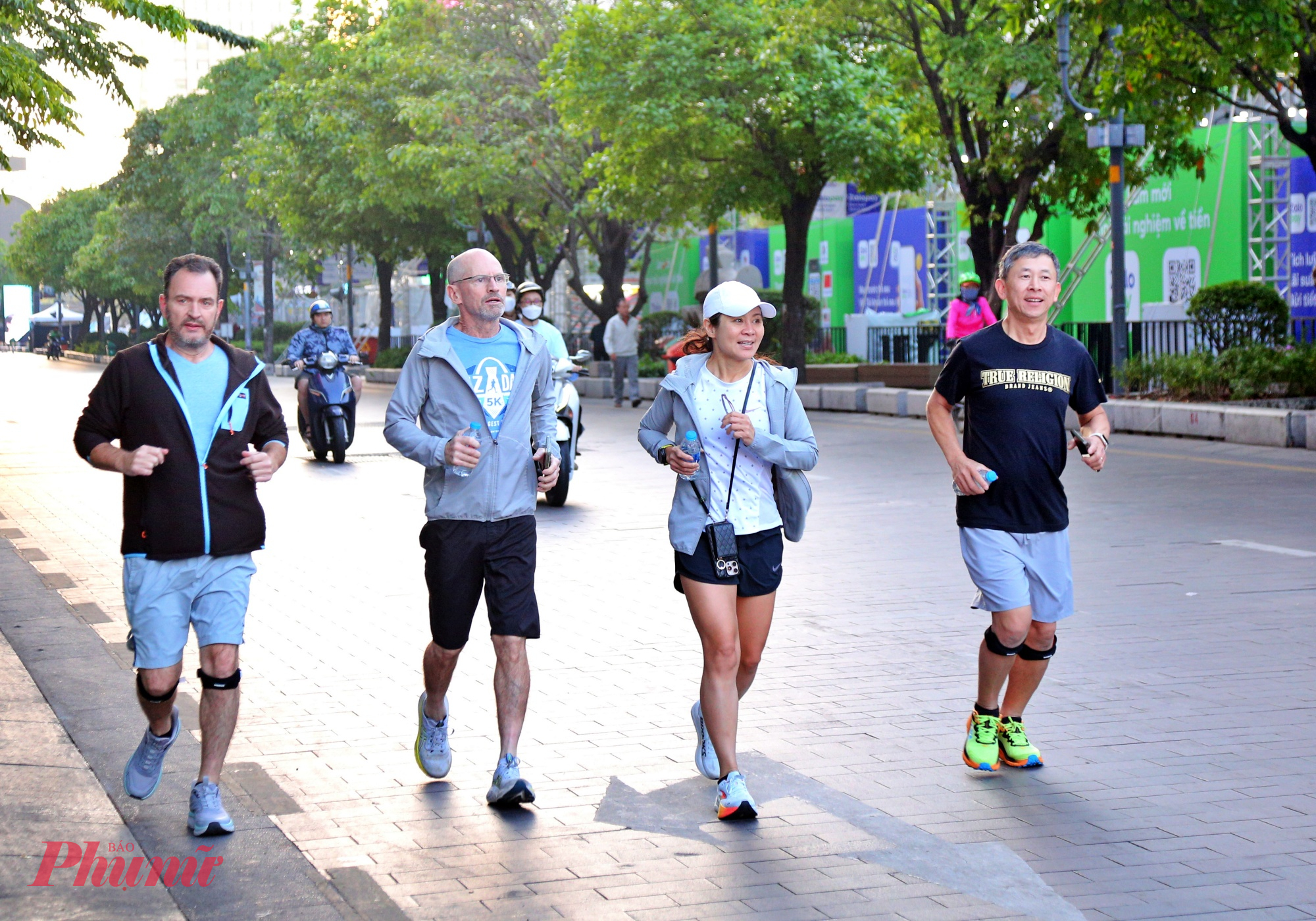 Một nhóm du khách chạy bộ tập thể dục trên phố đi bộ Nguyễn Huệ phải mặc áo khoác vì lanh