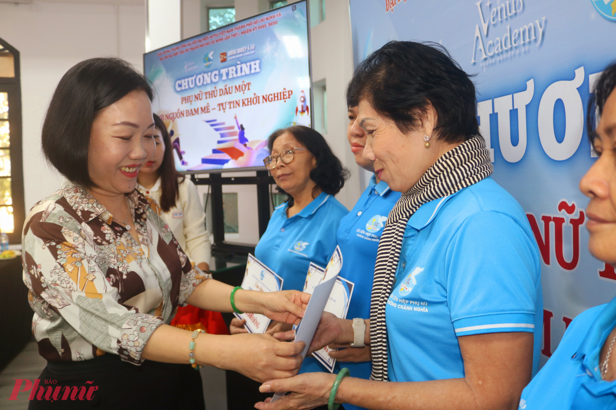 Bà Nguyễn Thu Cúc – Bí thư Đảng ủy, Chủ tịch HĐND phường Thủ Dâu Một – trao bảng tượng trưng thẻ bảo hiểm y tế cho các chị chi hội trưởng - Ảnh: Mẫn Nhi