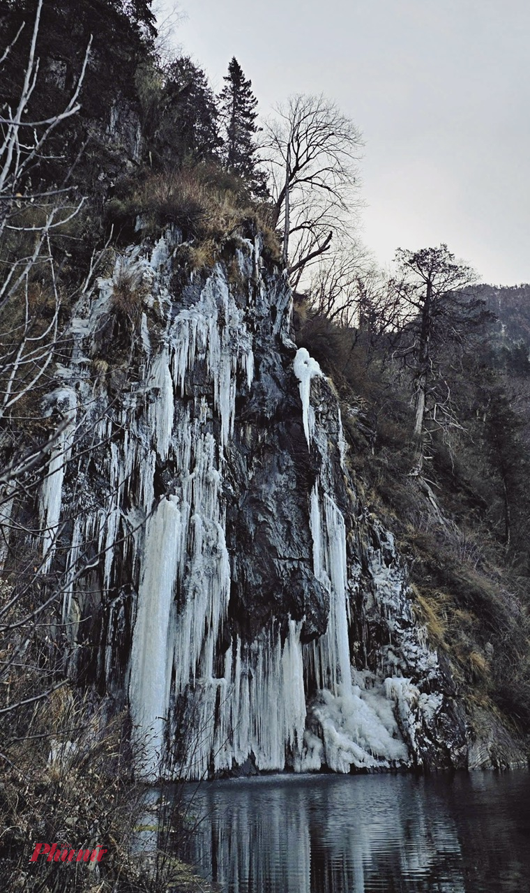 Những vách đá dựng đứng phủ kín thác băng, các mảng băng dài buông xuống sát mặt hồ tạo nên khung cảnh vừa kỳ vĩ vừa lạnh lẽo. Mặt hồ phẳng lặng phản chiếu núi rừng xung quanh, nước xen lẫn băng tạo nên sắc xanh xám đặc trưng của vùng cao nguyên lạnh giá.