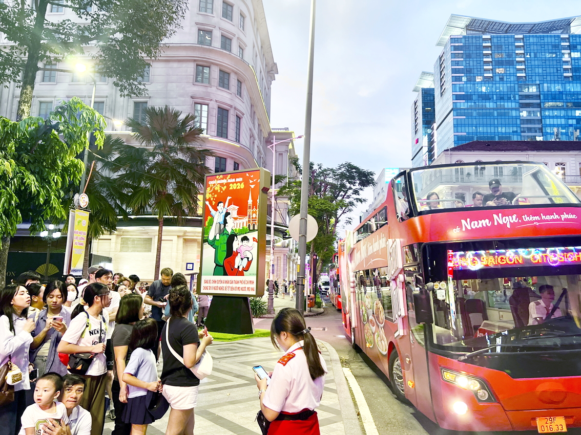 Đoàn du khách chuẩn bị lên buýt 2 tầng tham quan trung tâm TPHCM đêm Giáng sinh 2025 - ẢNH: QUỐC THÁI