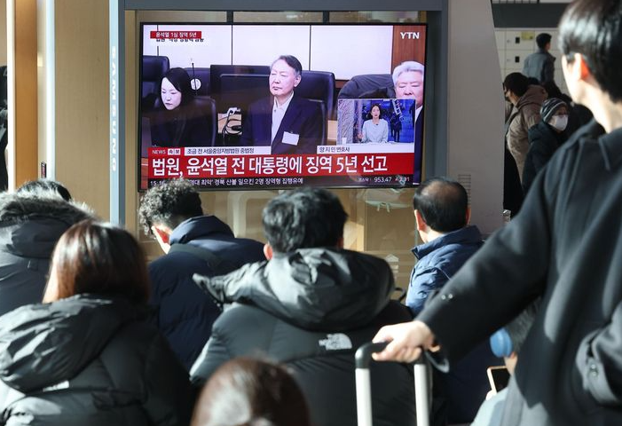 Những người đi làm tại ga Seoul xem một chương trình phát sóng trực tiếp phán quyết của cựu Tổng thống Yoon Suk Yeol về các cáo buộc liên quan đến thiết quân luật của ông, hôm thứ Sáu. Yonhap