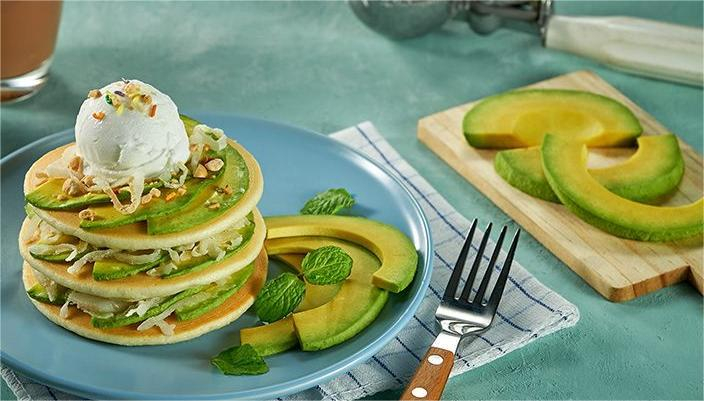 Pancake bơ – yến mạch mang lại trải nghiệm mới lạ vì kết cấu mềm ẩm hơn so với pancake thông thường. Trộn trứng, bơ và bột yến mạch xay, sau đó chiên trên chảo chống dính với lửa nhỏ để bánh vàng đều hai mặt. Có thể dùng kèm trái cây tươi hoặc chút mật ong nguyên chất để tăng vị mà không nạp đường tinh luyện. Yến mạch là nguồn carb lành mạnh, giàu beta-glucan giúp kiểm soát mỡ máu và đường huyết. Bơ trong công thức không chỉ làm bánh ngon hơn mà còn cung cấp vitamin nhóm B hỗ trợ chuyển hóa năng lượng, đồng thời vitamin E giúp cải thiện độ đàn hồi da. Đây là bữa sáng lý tưởng cho những ngày cần năng lượng kéo dài nhưng vẫn muốn giữ vòng eo thanh mảnh.