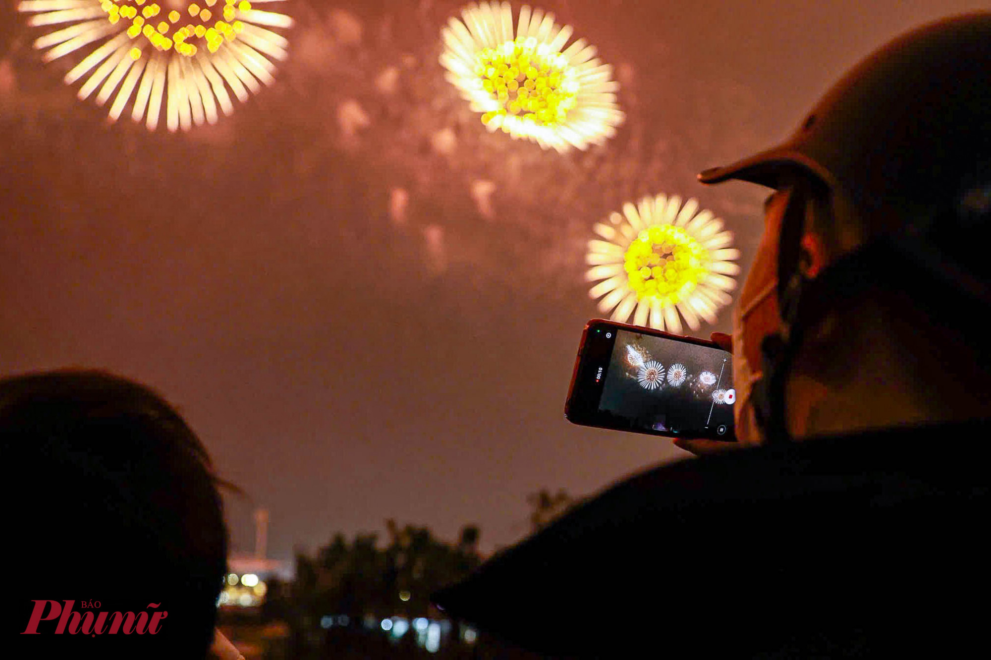 Mặc dù trong tối 21/1, nhiệt độ tại Hà Nội giảm mạnh ở mức 12-13 độ C, hằng trăm người dân vẫn đội mưa rét đến xem pháo hoa.