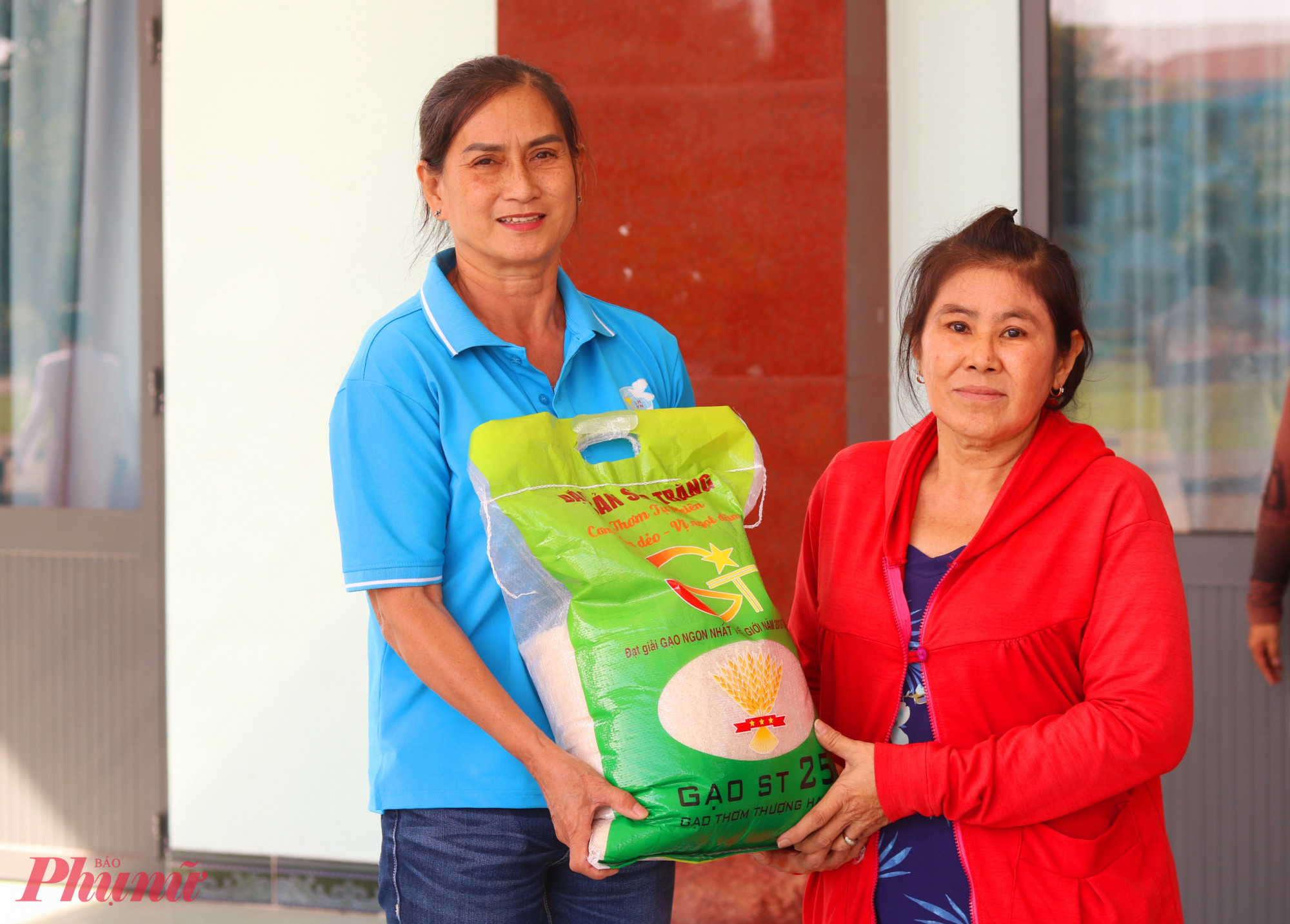 Vì đi lại khó khăn, bà Nguyễn Thị Hòa (bìa phải) được Chi hội trưởng Chi hội Phụ nữ khu phố Bình Đức 1 Ngô Thị Xuân Hương hỗ trợ di chuyển và lãnh quà - Ảnh: Mẫn Nhi