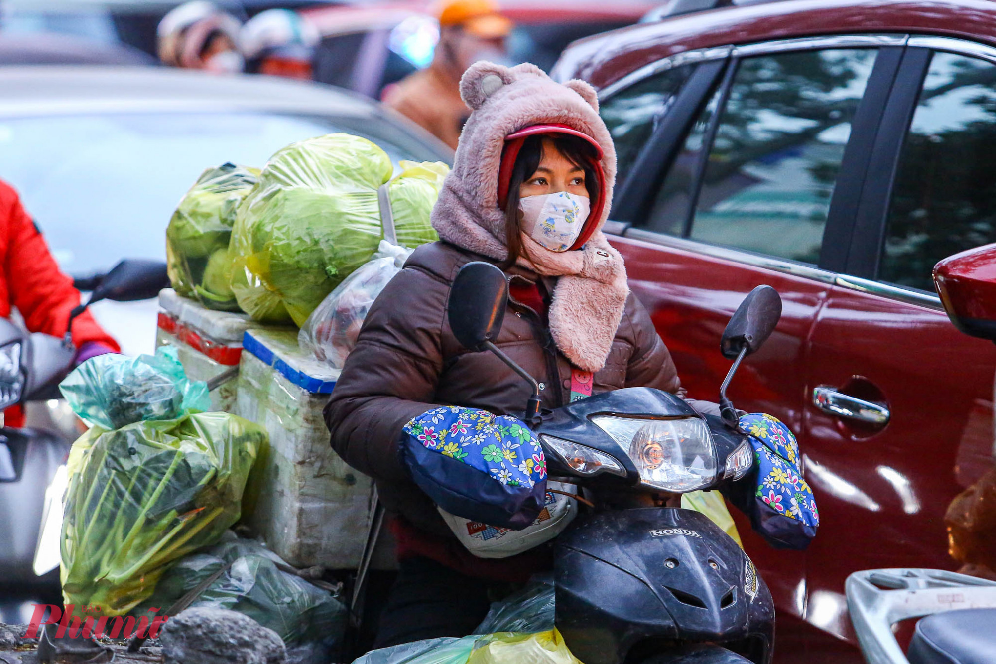 Chị Ngọc Hà (trú tại phường Đông Ngạc) chia sẻ trong khi đang dừng đèn đỏ: 'Dù đã mặc 4 lớp áo và khoác thêm áo mưa để chắn gió nhưng hơi lạnh vẫn len lỏi vào người. Cầm tay lái mà đôi bàn tay tê cứng, cảm giác như không còn cảm giác.'