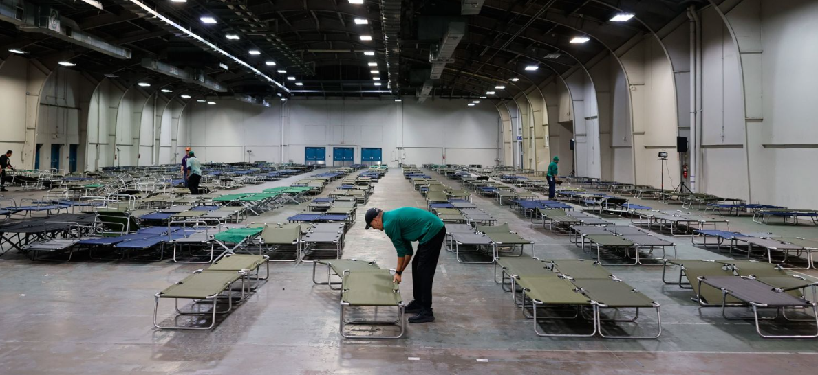 Các tình nguyện viên chuẩn bị cũi tại một nơi trú ẩn khẩn cấp tại Tòa nhà Ô tô của Fair Park ở Dallas vào thứ Sáu, ngày 23 tháng 1. Hình ảnh Mark Felix / Bloomberg / Getty