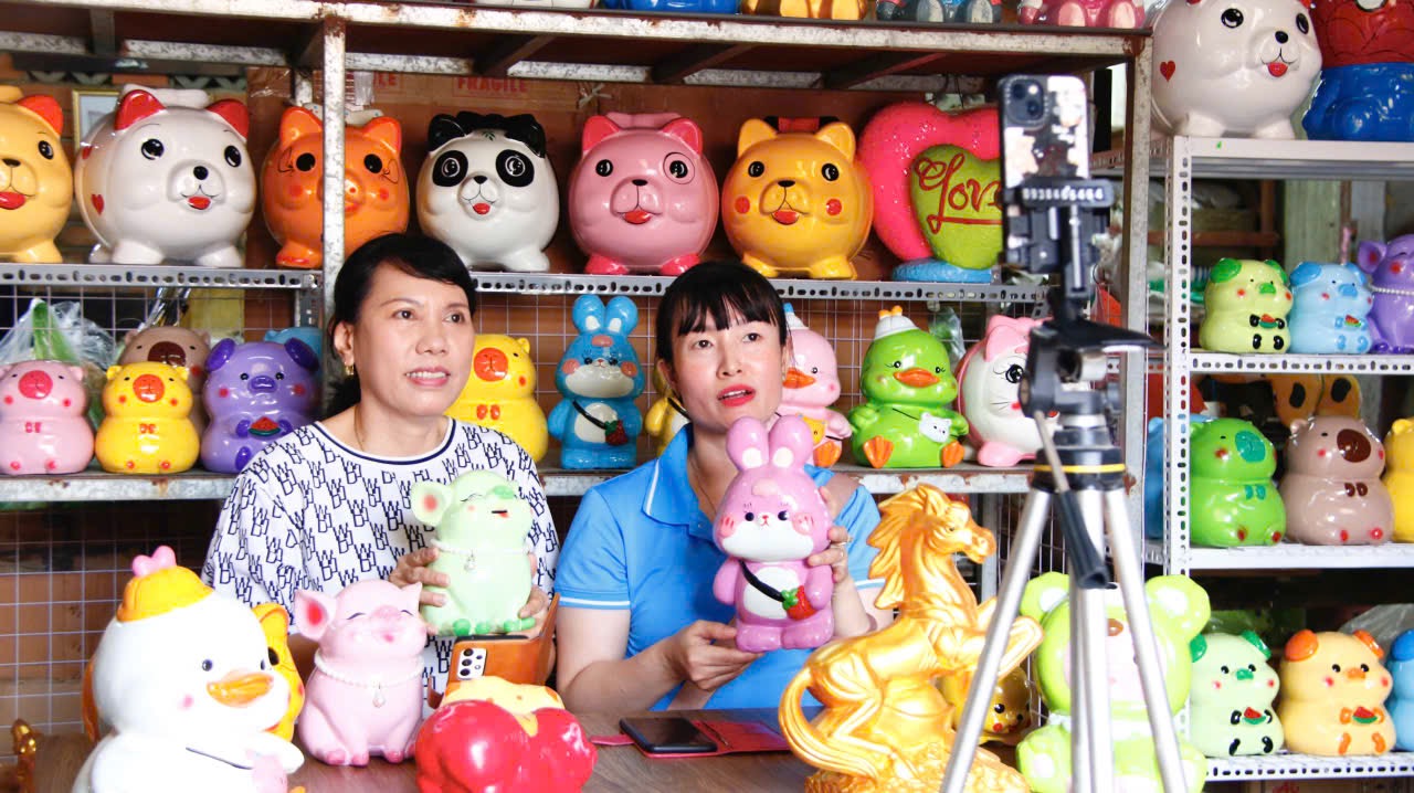 Nông dân sớm chốt nhiều đơn hàng tết nhờ chủ động rao bán trên mạng Chị Nguyễn Thị Cẩm Hường (bìa phải) và bà Nguyễn Thị Thu Hà – Chủ cơ sở heo đất Hà An tại khu phố Chánh Nghĩa 7, phường Thủ Dầu Một đang livestream bán sản phẩm tại xưởng