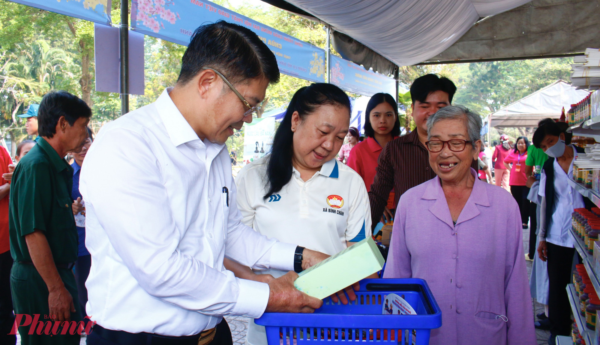 Bà Nguyễn Thị Thơm (75 tuổi), ngụ ấp 13, xã Bình Chánh (bìa phải) hiện sống một mình, con cái có gia đình riêng cũng còn nhiều khó khăn. Bà mắc bệnh cao huyết áp và tiểu đường nên không còn khả năng lao động như trước. Những năm còn khỏe, ai thuê gì bà cũng làm, mỗi ngày kiếm được vài chục nghìn đồng để mua mắm muối, tạm bữa qua ngày. Tết sắp đến, bà Thơm cũng không dám nghĩ đến chuyện sắm sửa gì. Hôm nay, đến “Phiên chợ 0 đồng” để nhận quà miễn phí, bà Thơm không giấu được niềm vui. Bà hồ hởi lựa bánh trái, gia vị,… và cho biết những phần quà này giúp bà có thêm thực phẩm cho những ngày Tết sắp tới, lòng cũng ấm áp hơn khi cảm nhận được sự quan tâm, sẻ chia của cộng đồng.